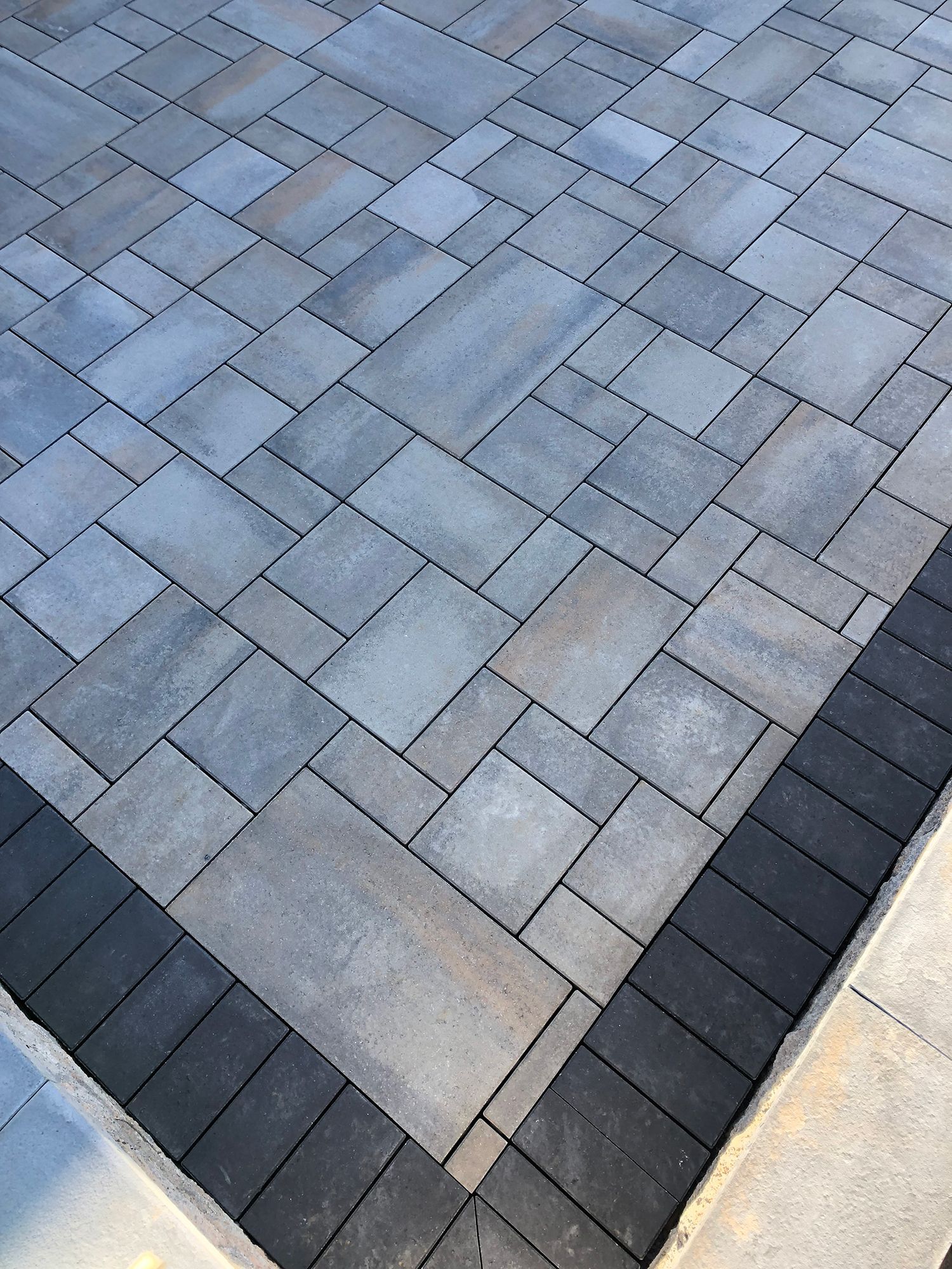 A close up of a brick driveway with a black border.