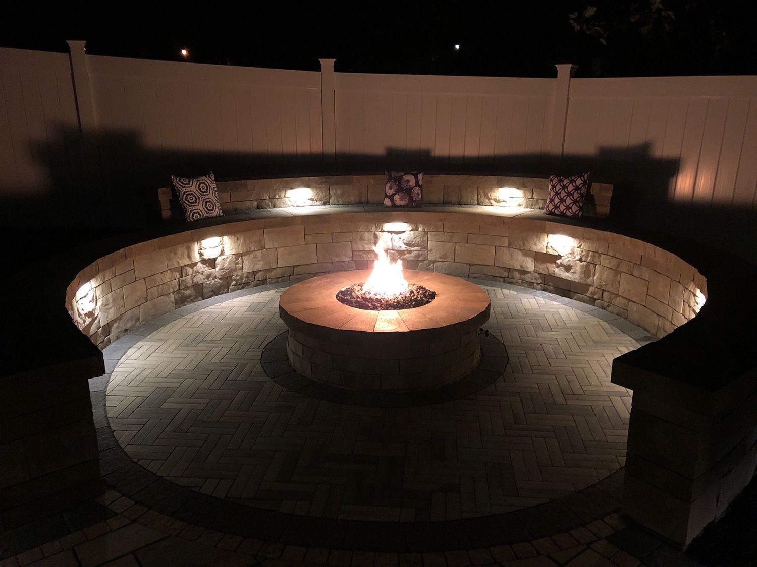 There is a fire pit in the middle of the patio at night.