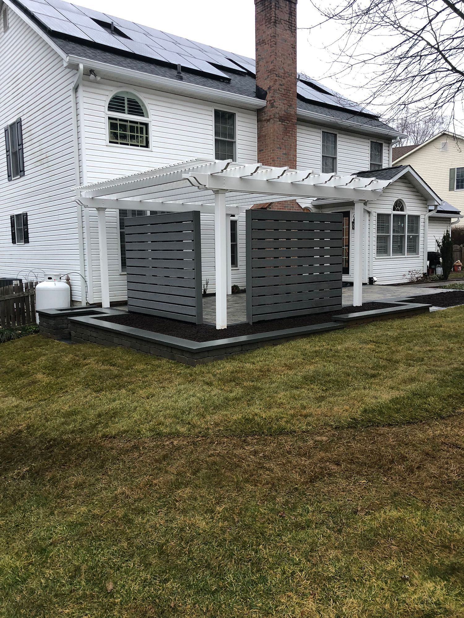 A white house with a pergola in front of it.