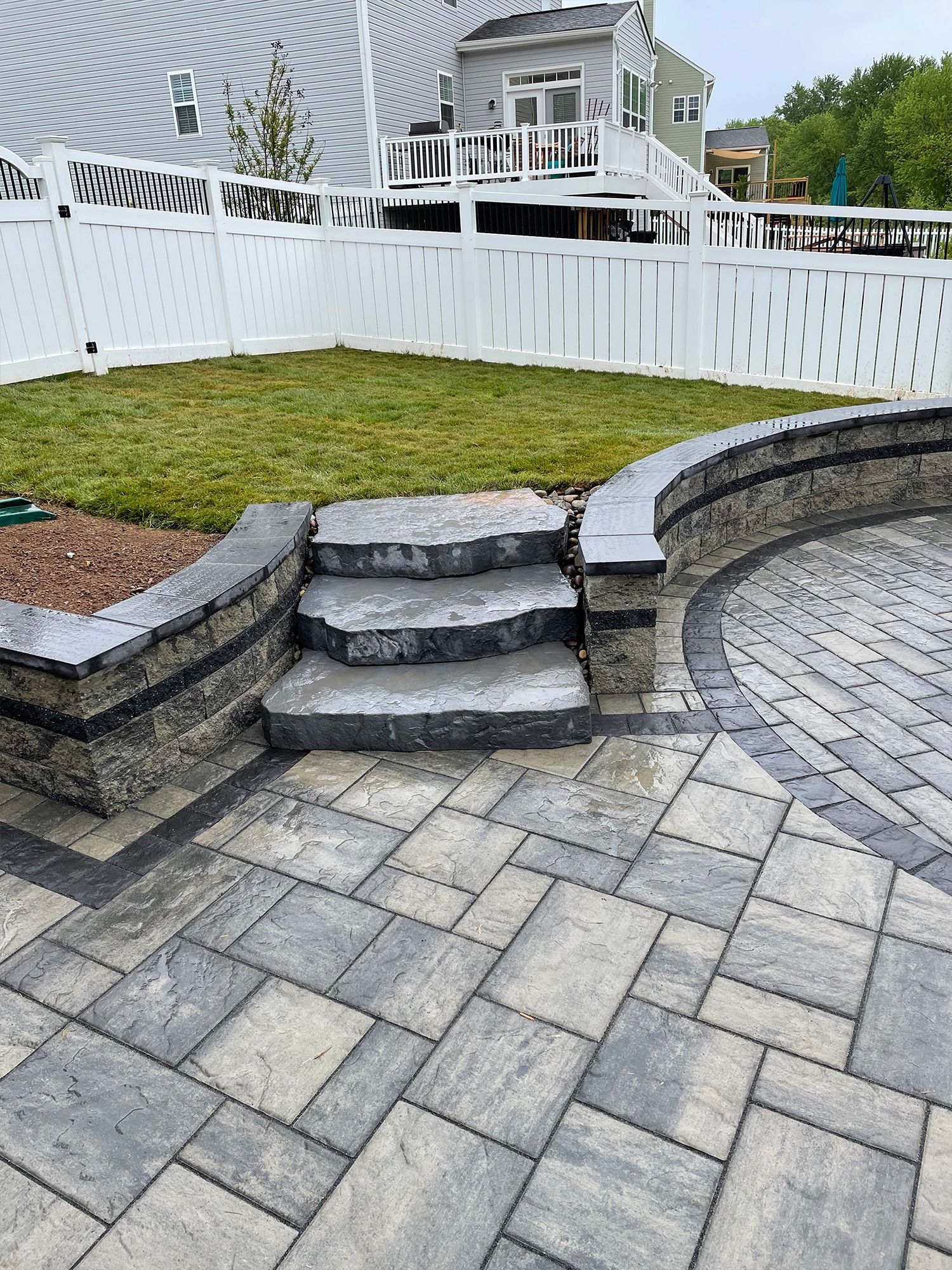 A patio with stairs and a wall in front of a house.