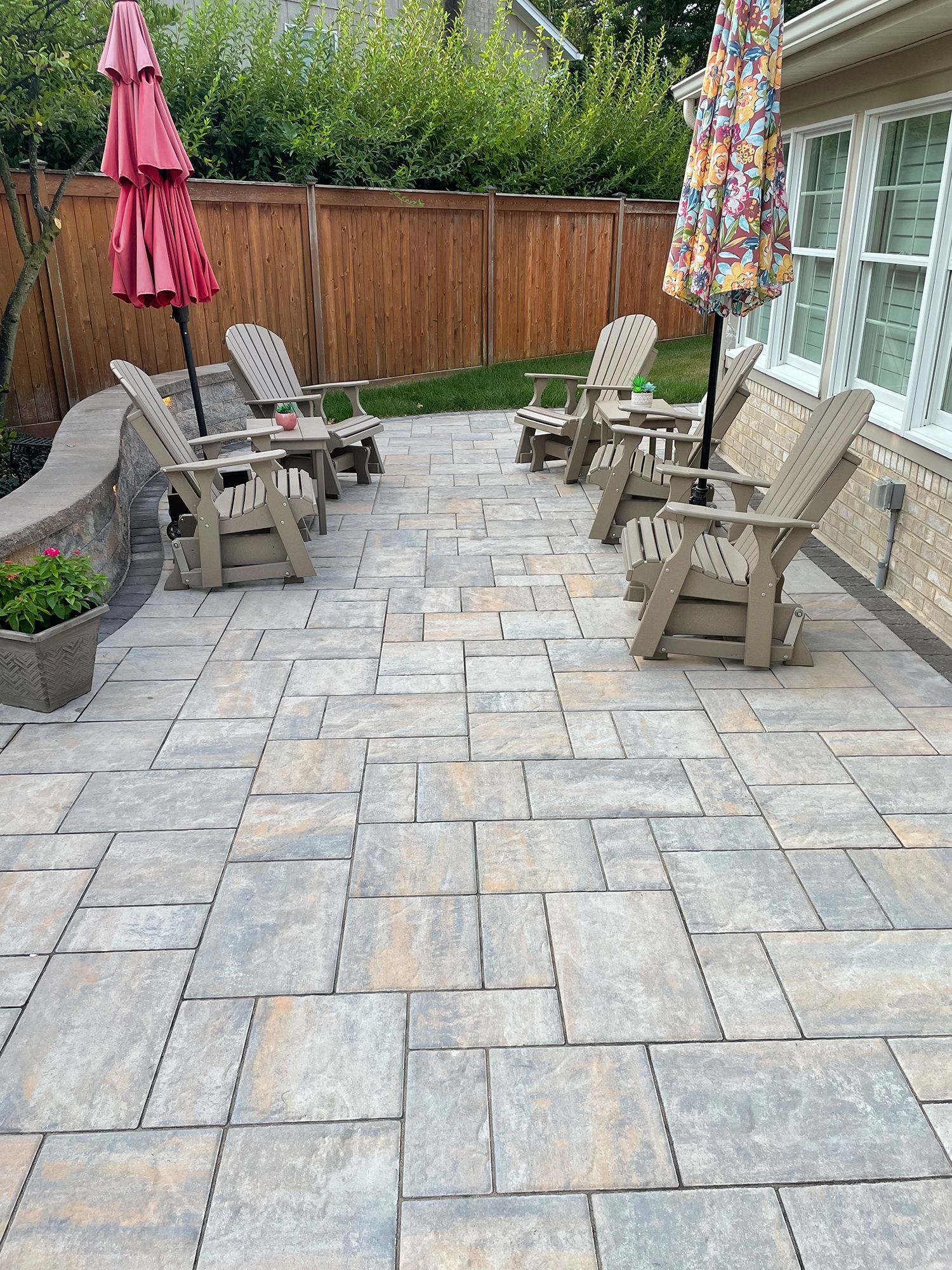 A patio with chairs and umbrellas in front of a house.
