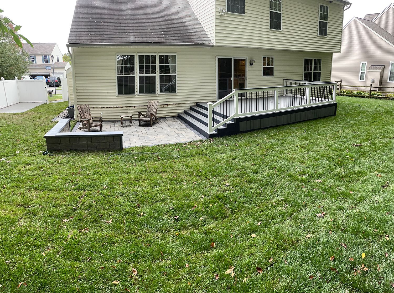The backyard of a house with a large deck and patio.