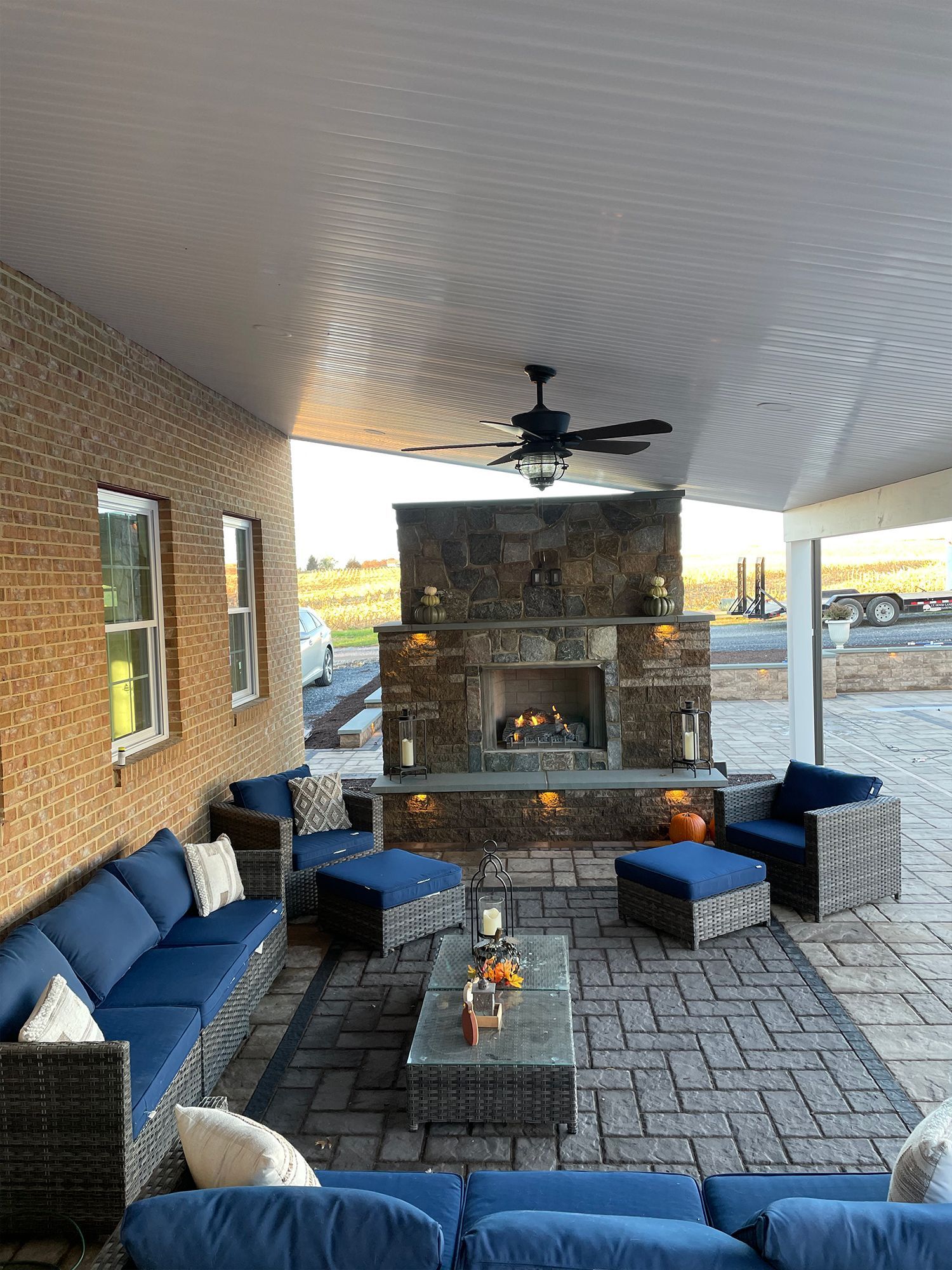 There is a fireplace in the backyard with a ceiling fan.