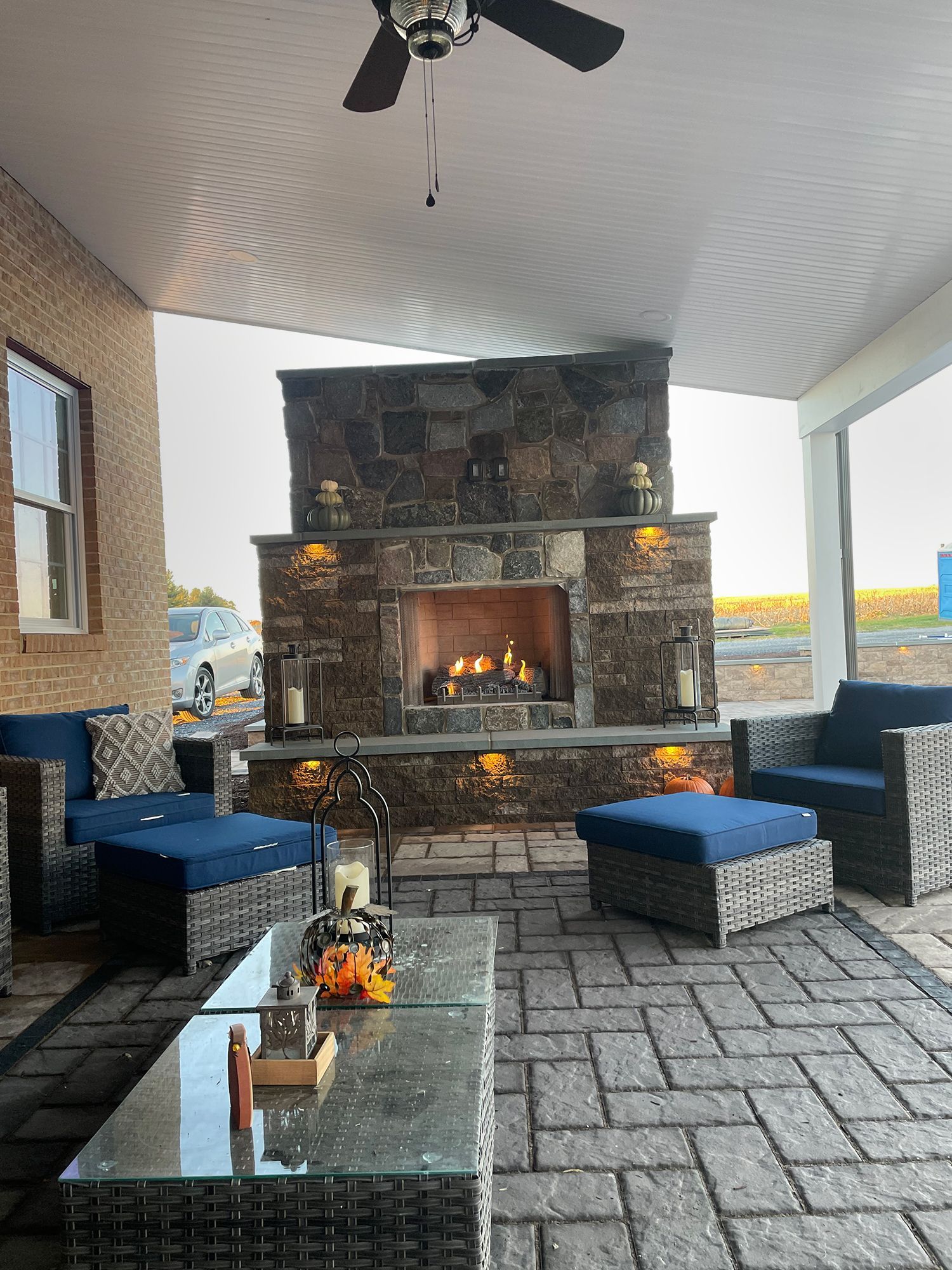 A patio with a fireplace and a ceiling fan.