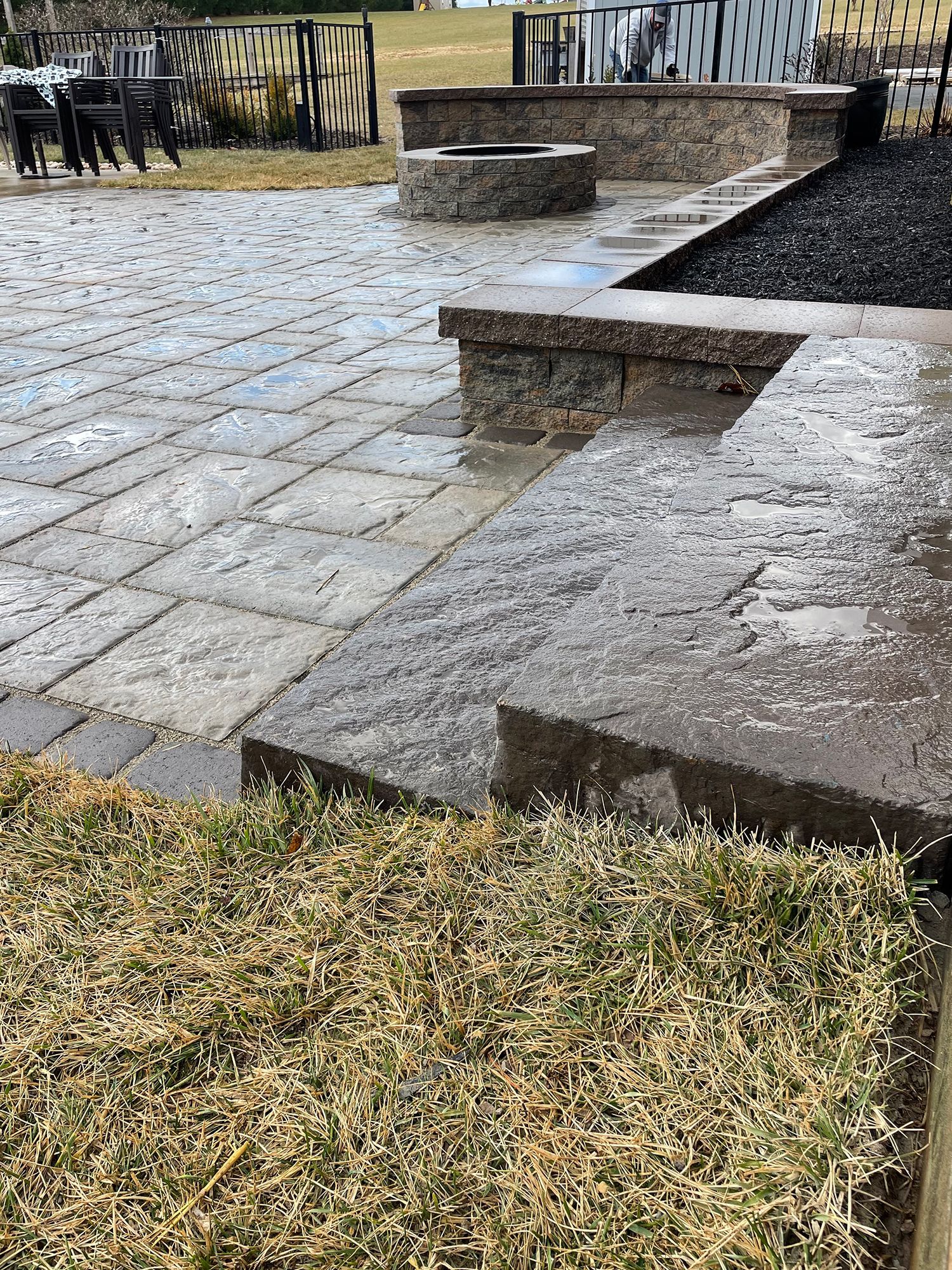 A brick patio with a fire pit in the middle of it.