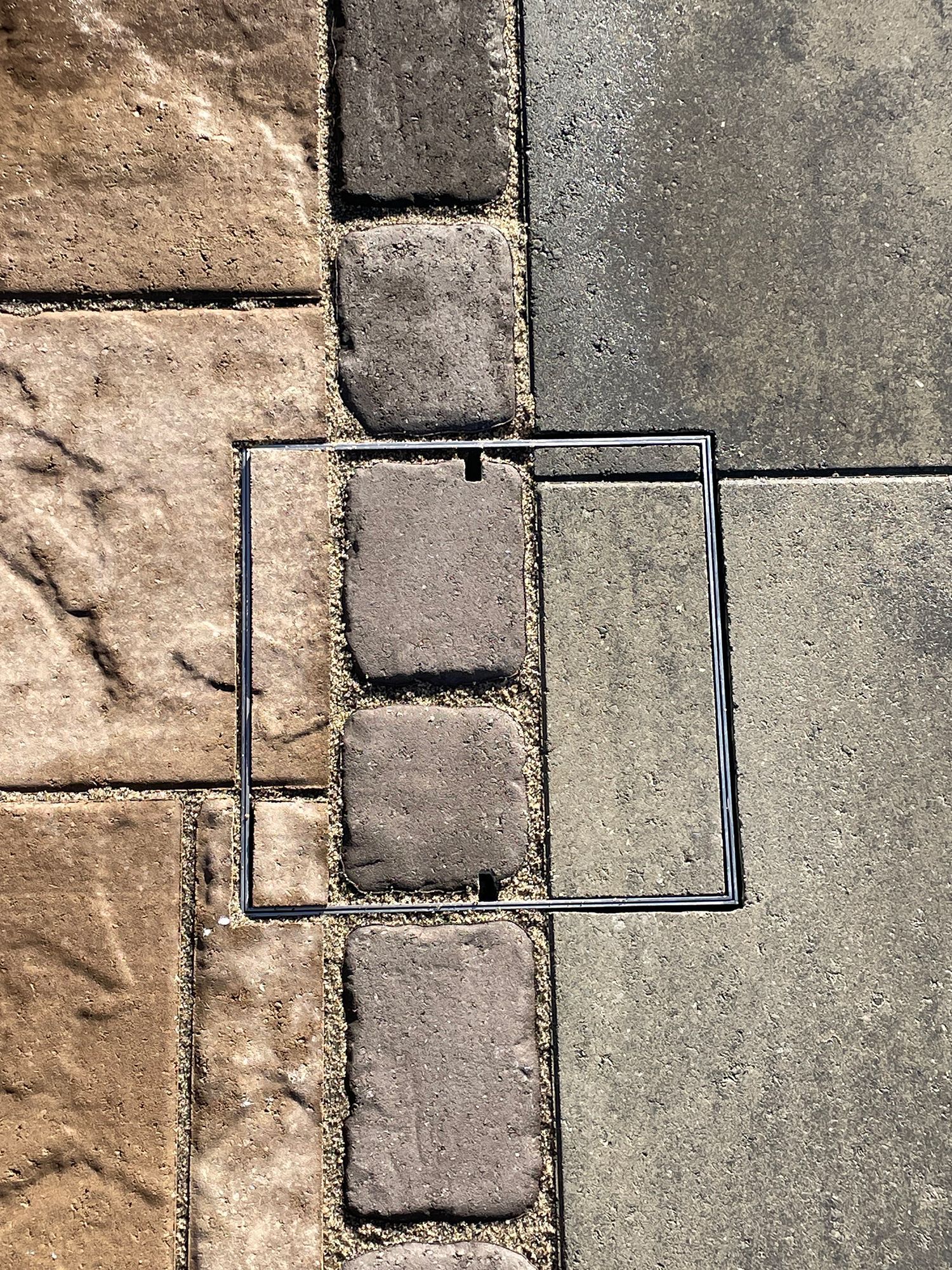 A close up of a brick walkway with a metal frame.