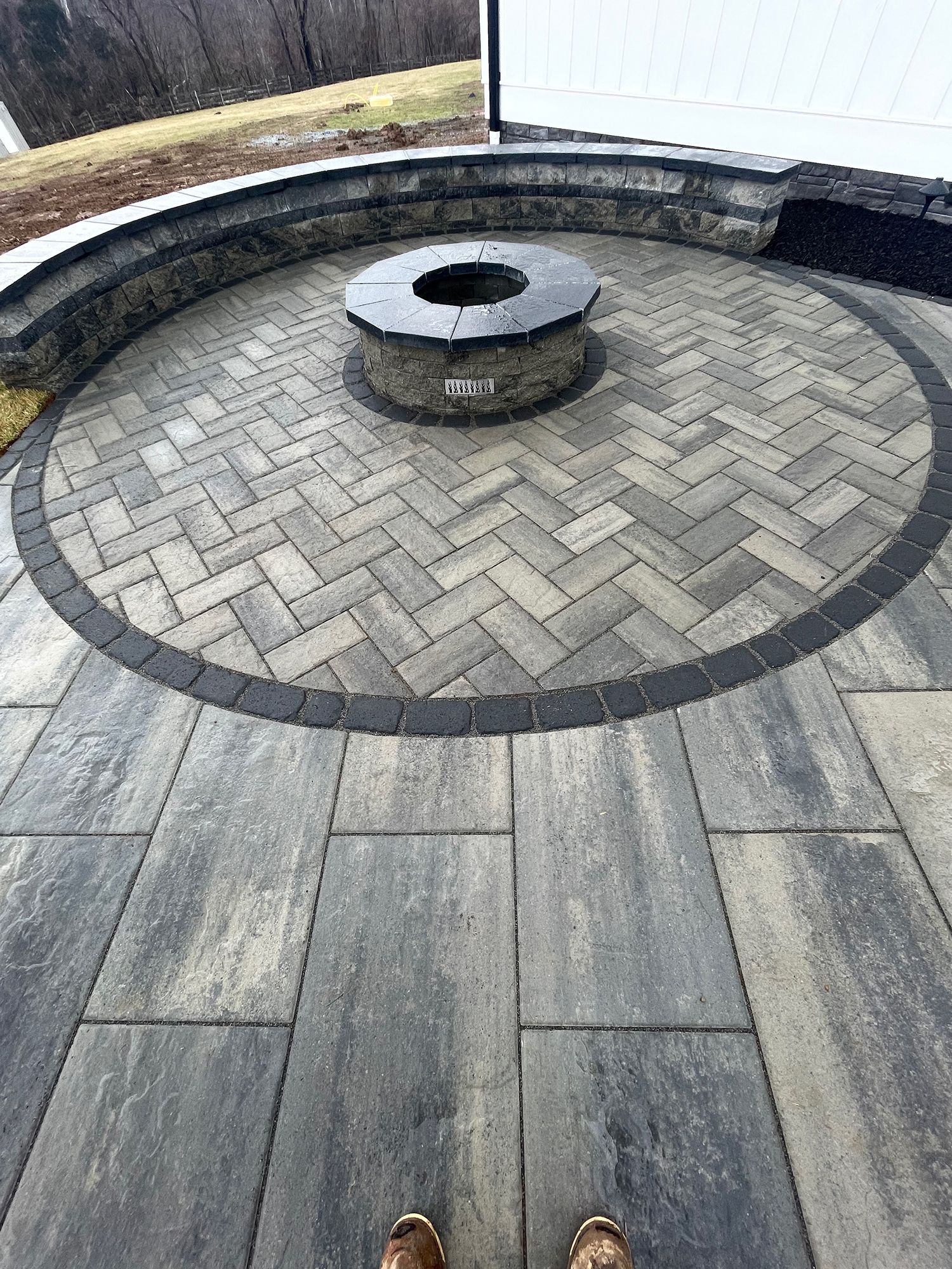 A person is standing on a patio with a fire pit in the middle.