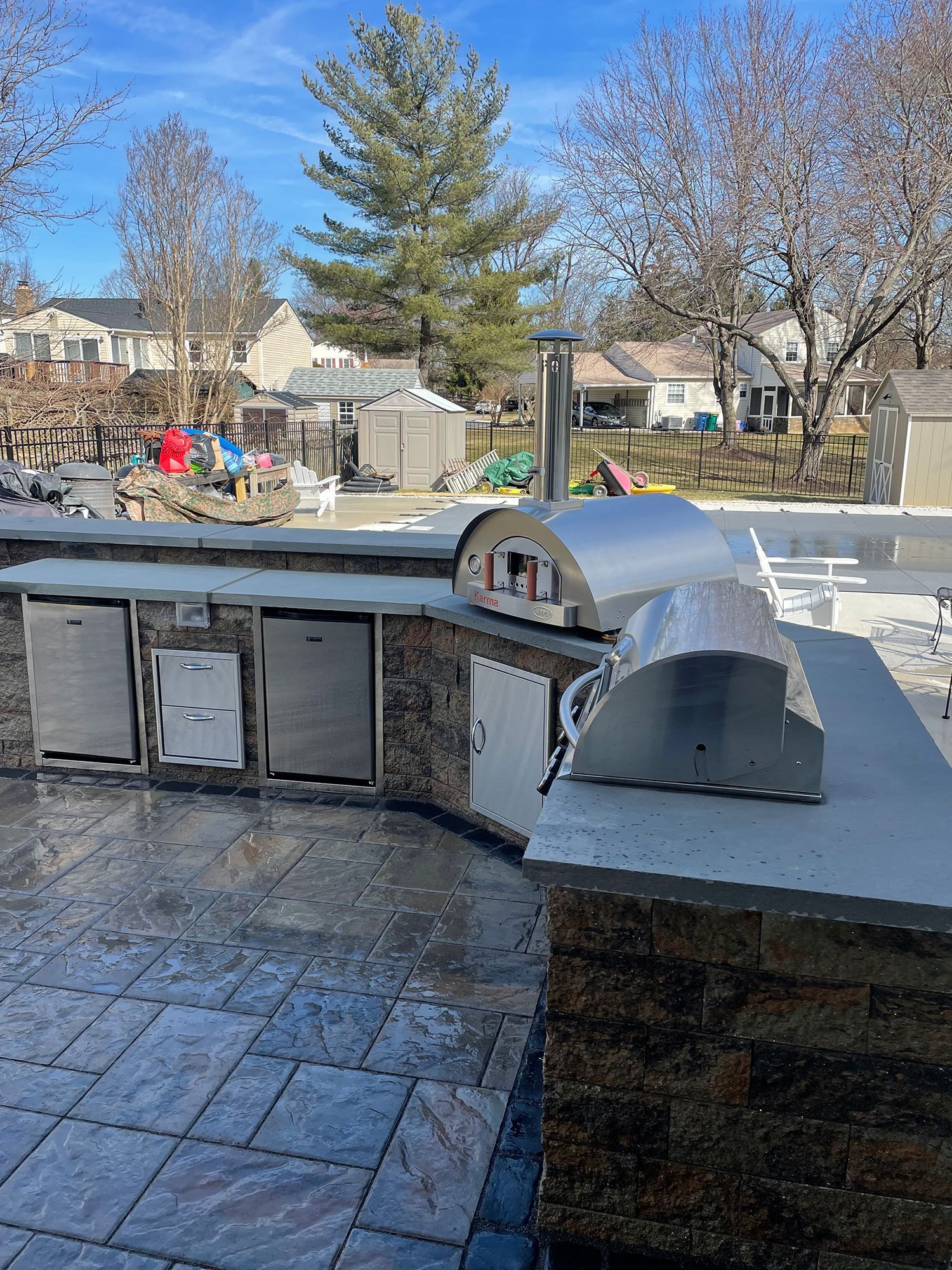 A large outdoor kitchen with a pizza oven and a grill.