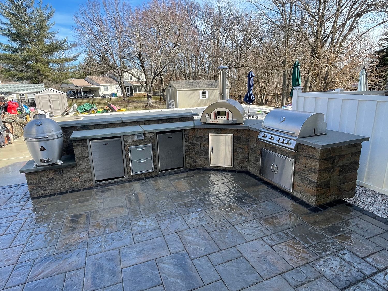 A large outdoor kitchen with a grill and a pizza oven.