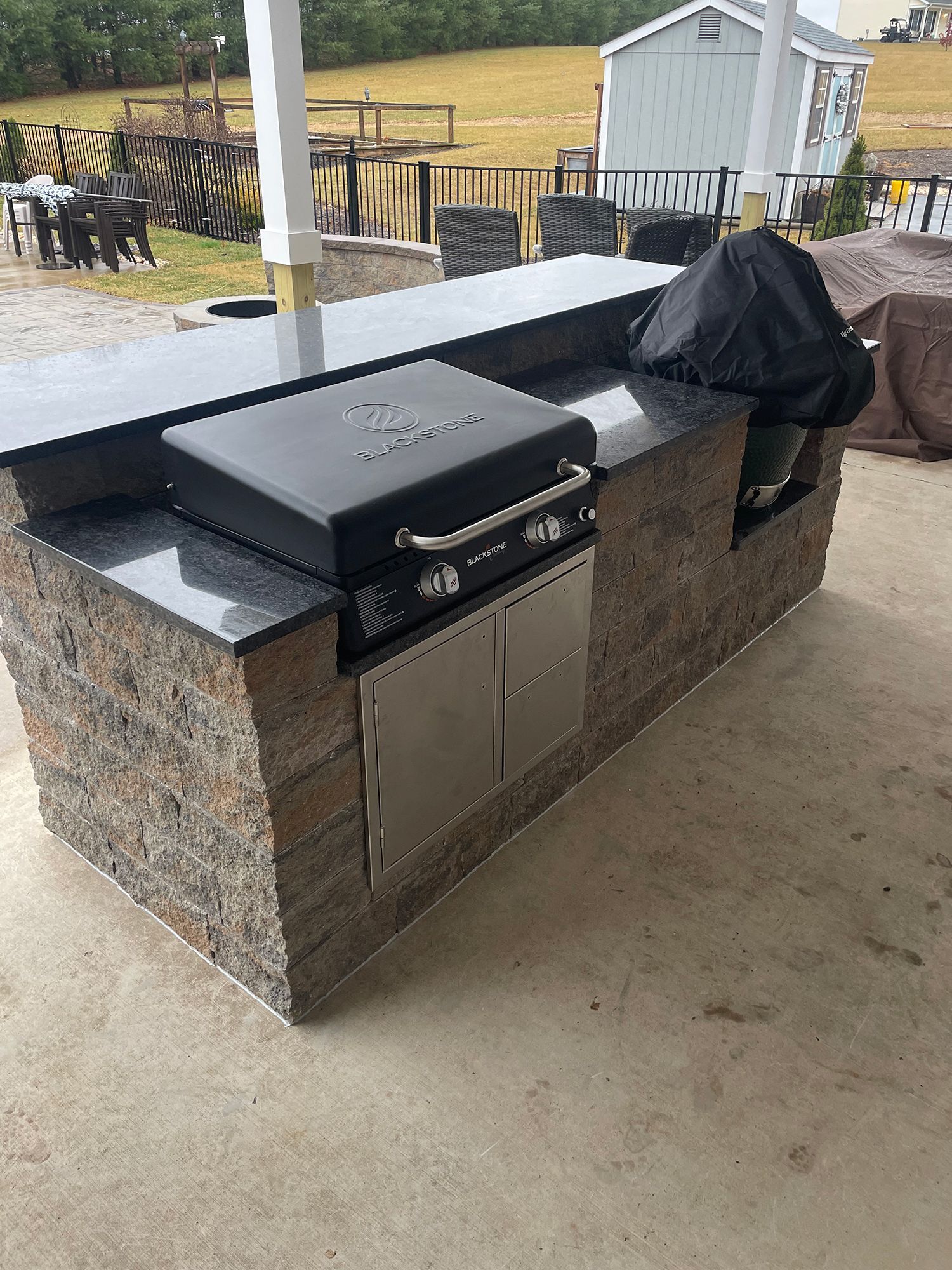 A grill is sitting on top of a counter in an outdoor kitchen.