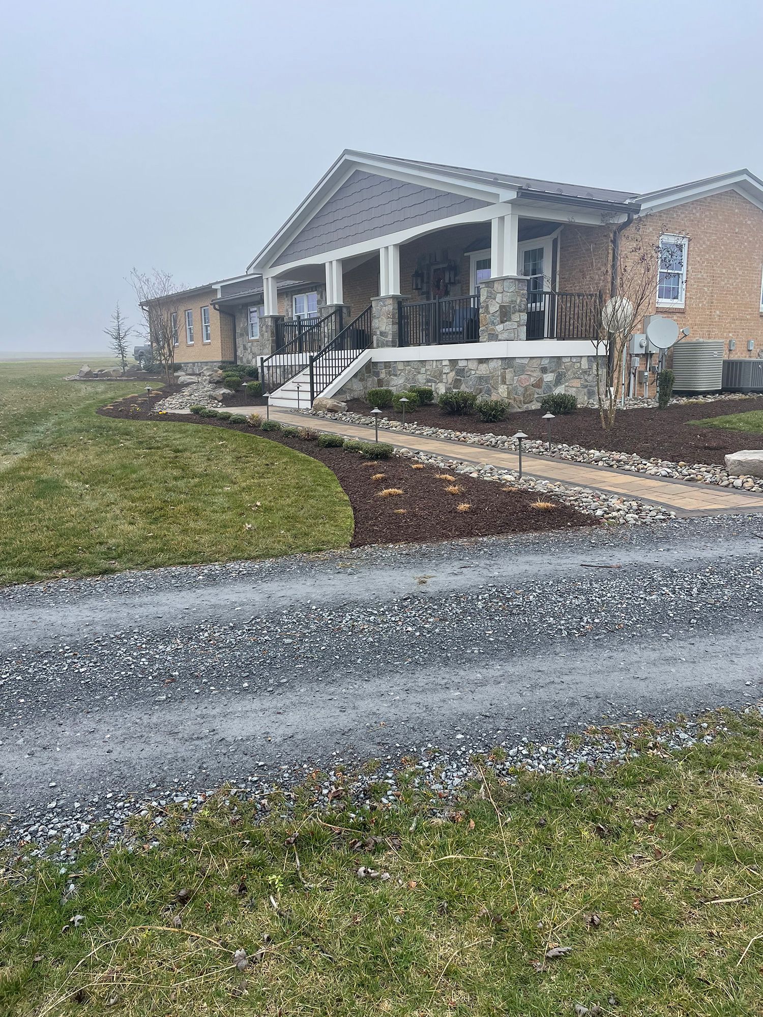 A house is sitting on top of a grassy hill next to a road.