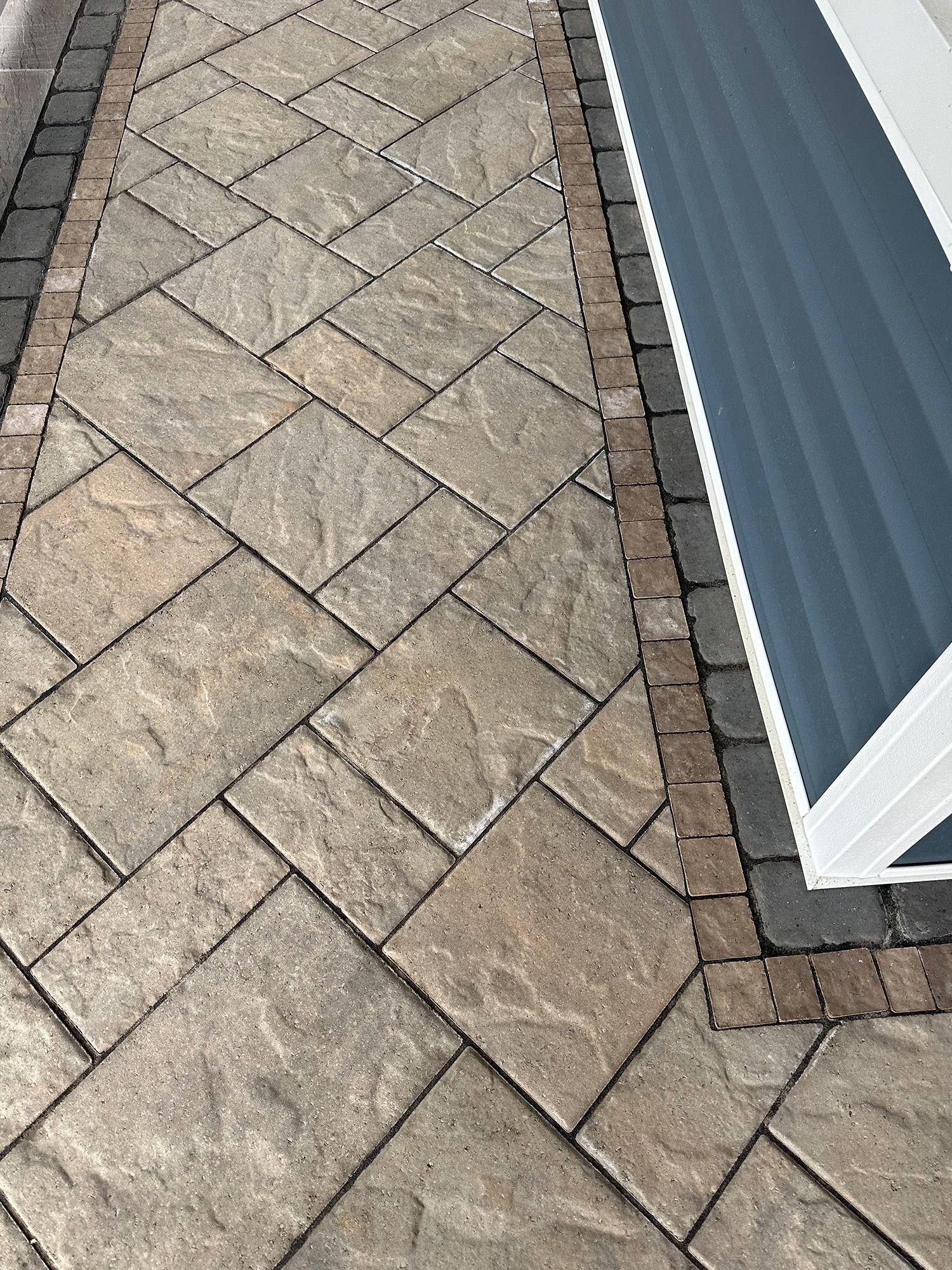 A close up of a brick walkway next to a house.