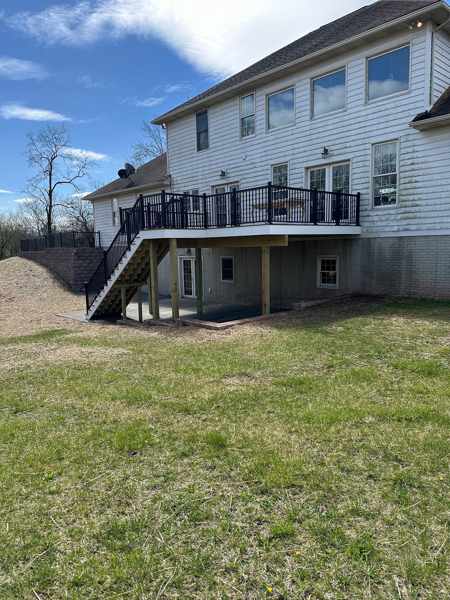 A large white house with a large deck in the backyard.