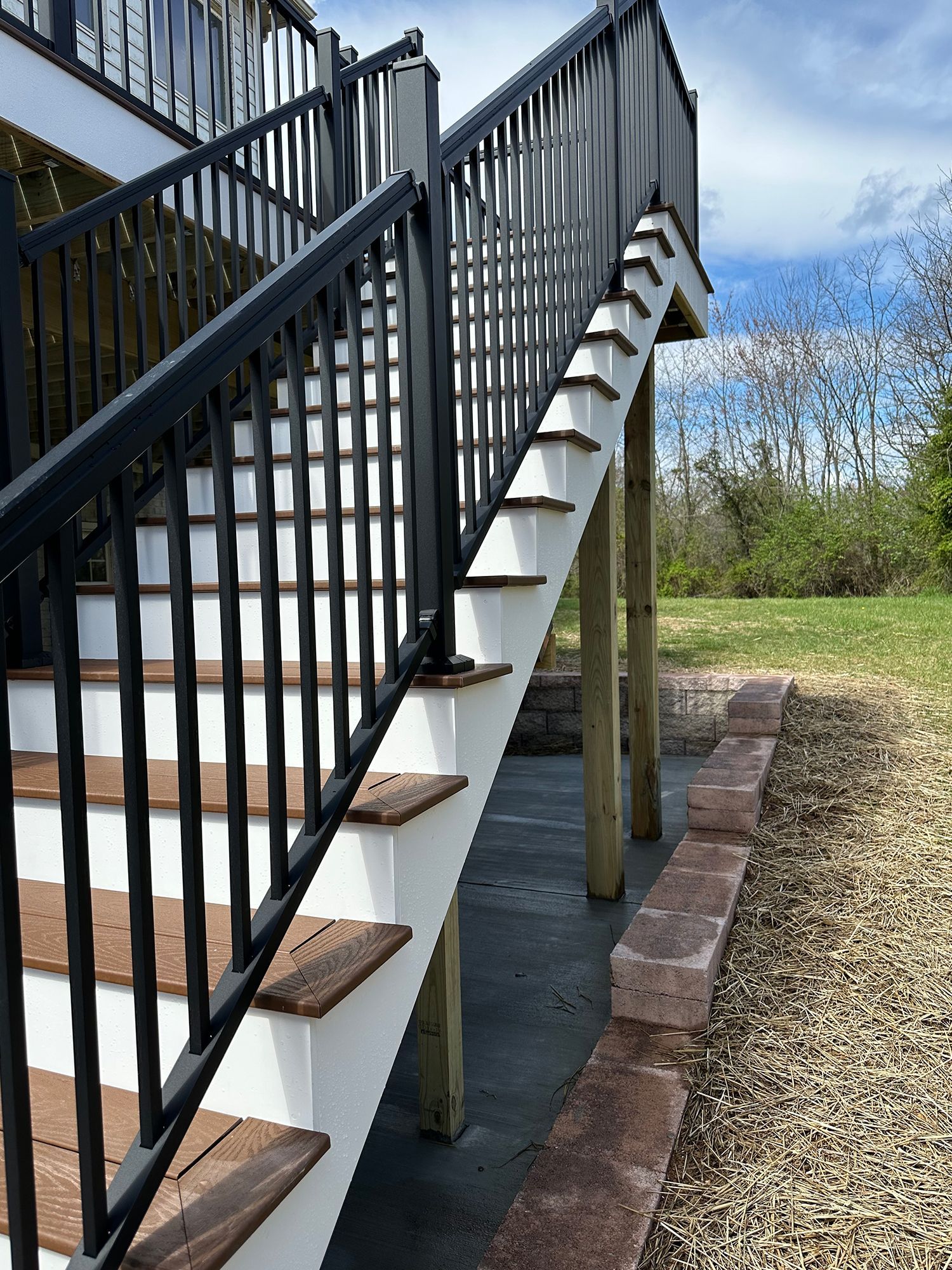 A set of stairs leading up to a deck with a black railing.