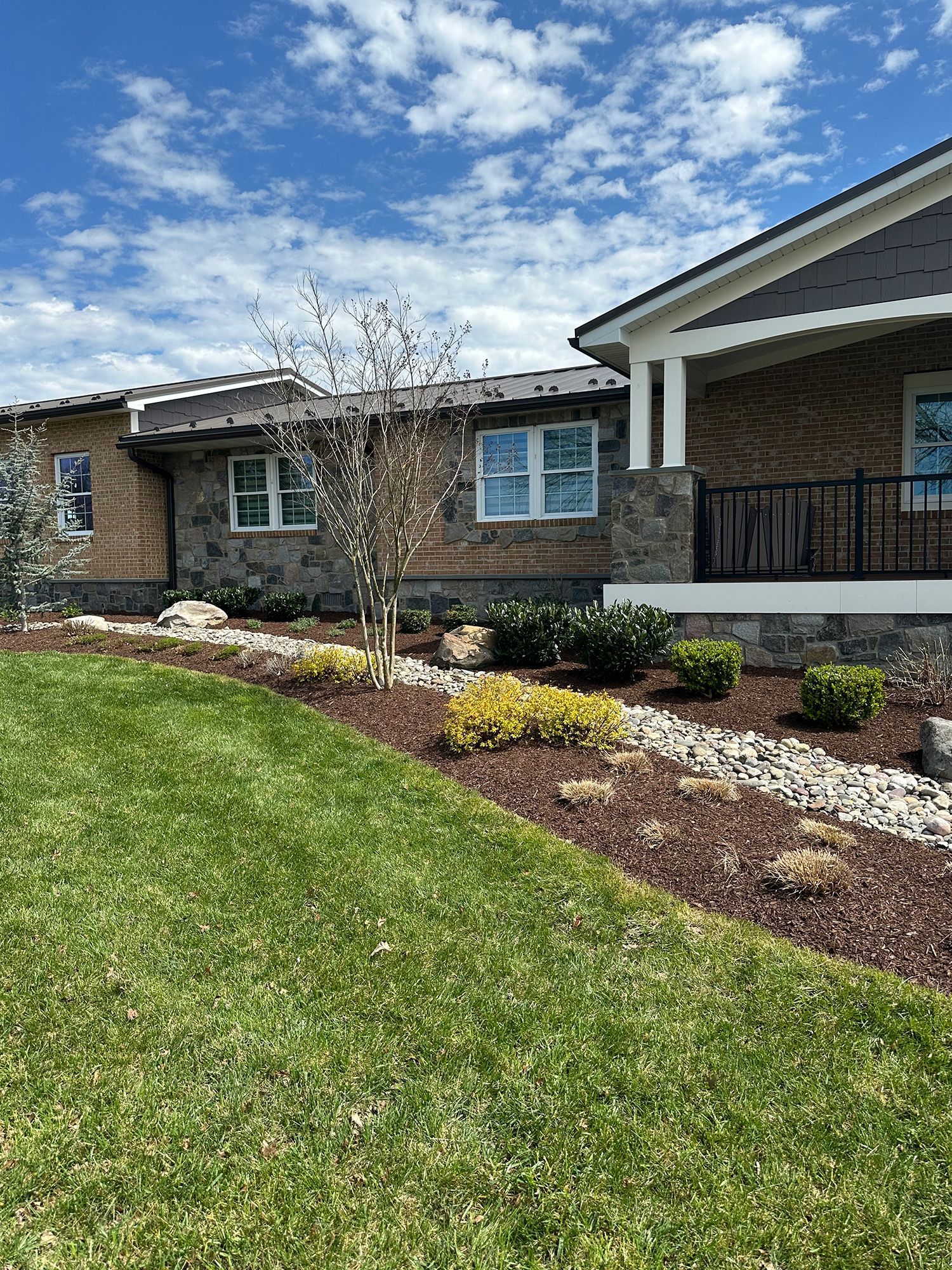 A large brick house with a large lawn in front of it.