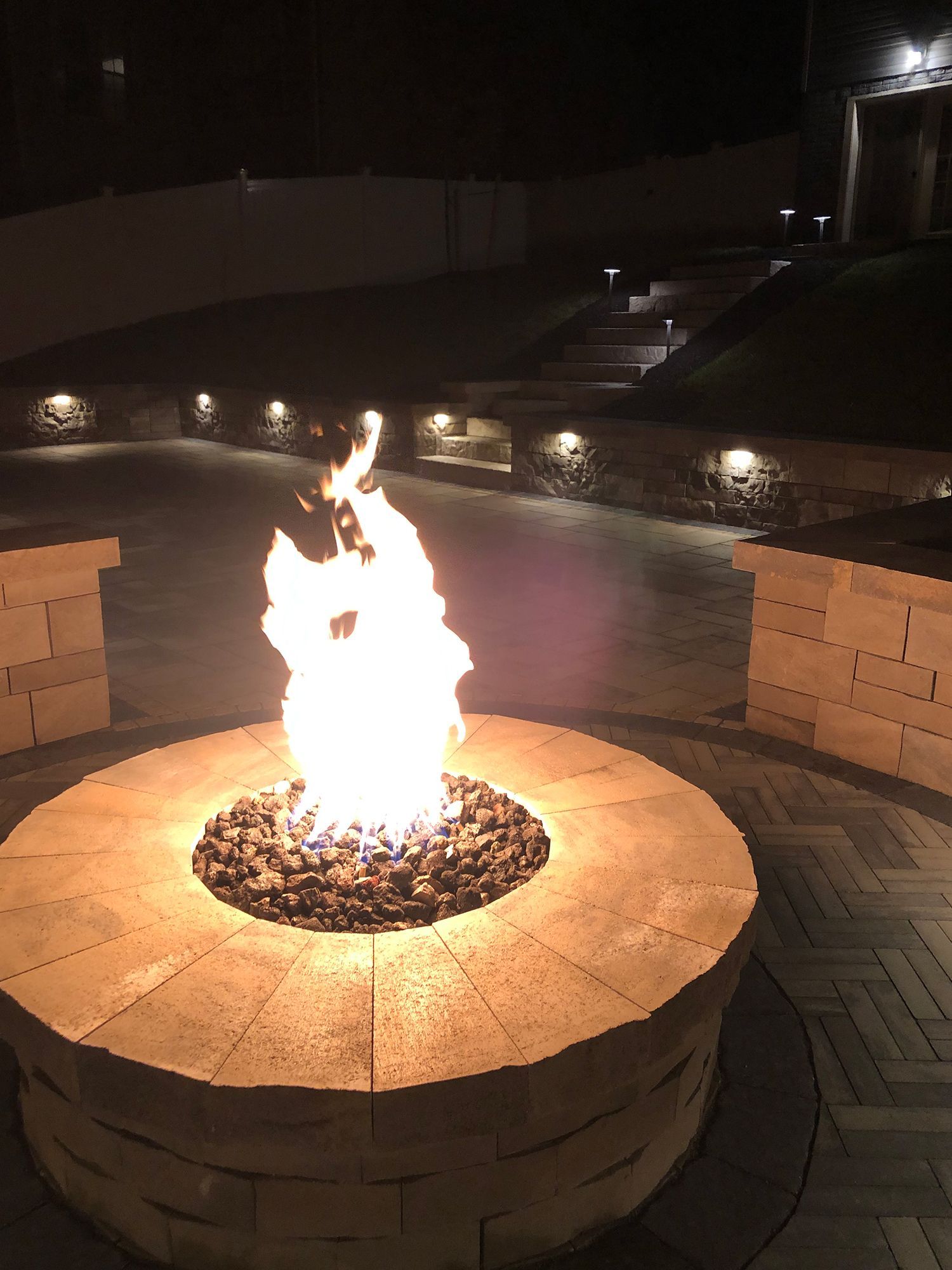 A fire pit is lit up at night in a backyard