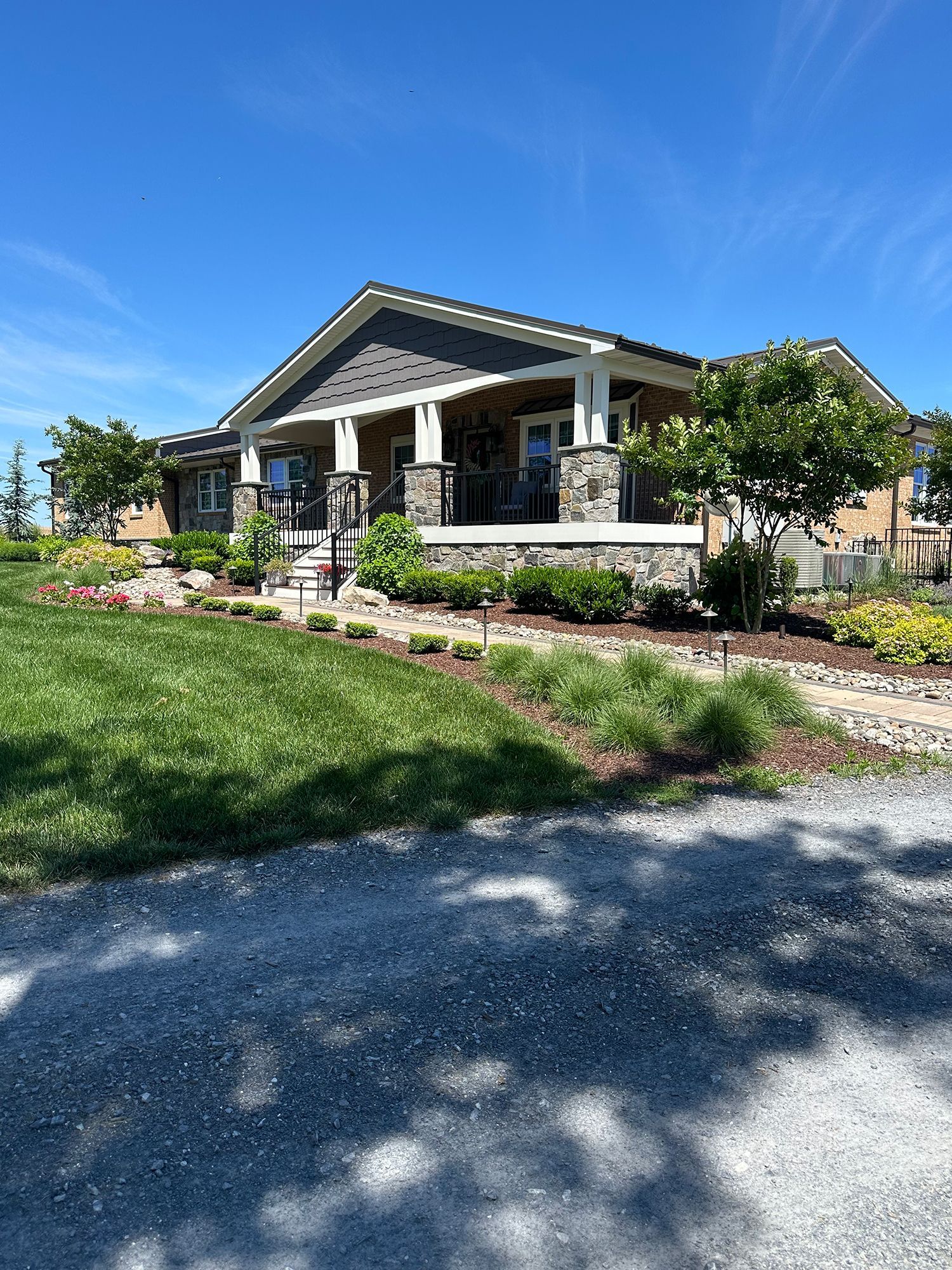 A large house with a large porch is sitting on top of a lush green field.