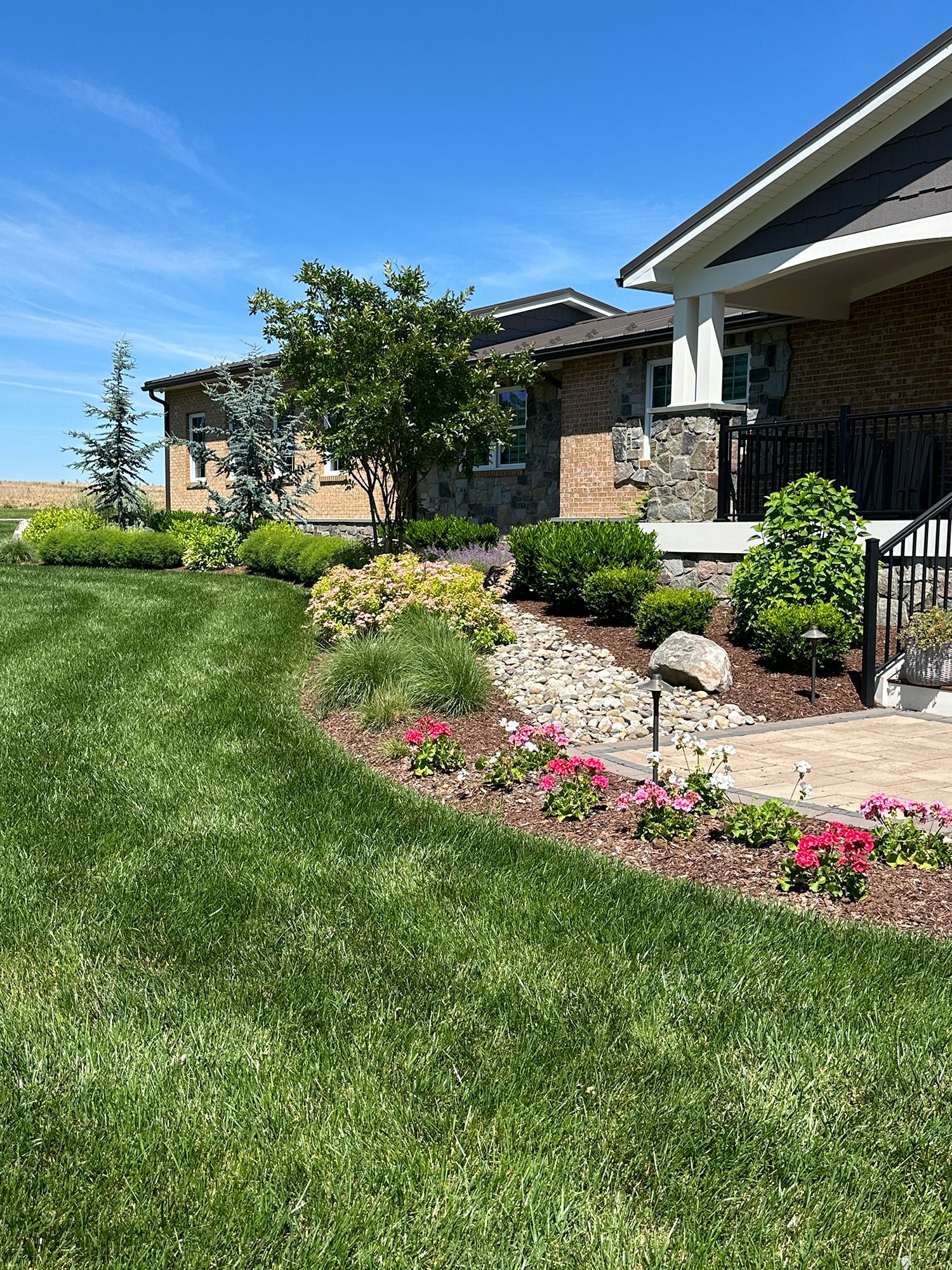 A house with a lush green lawn and flowers in front of it.