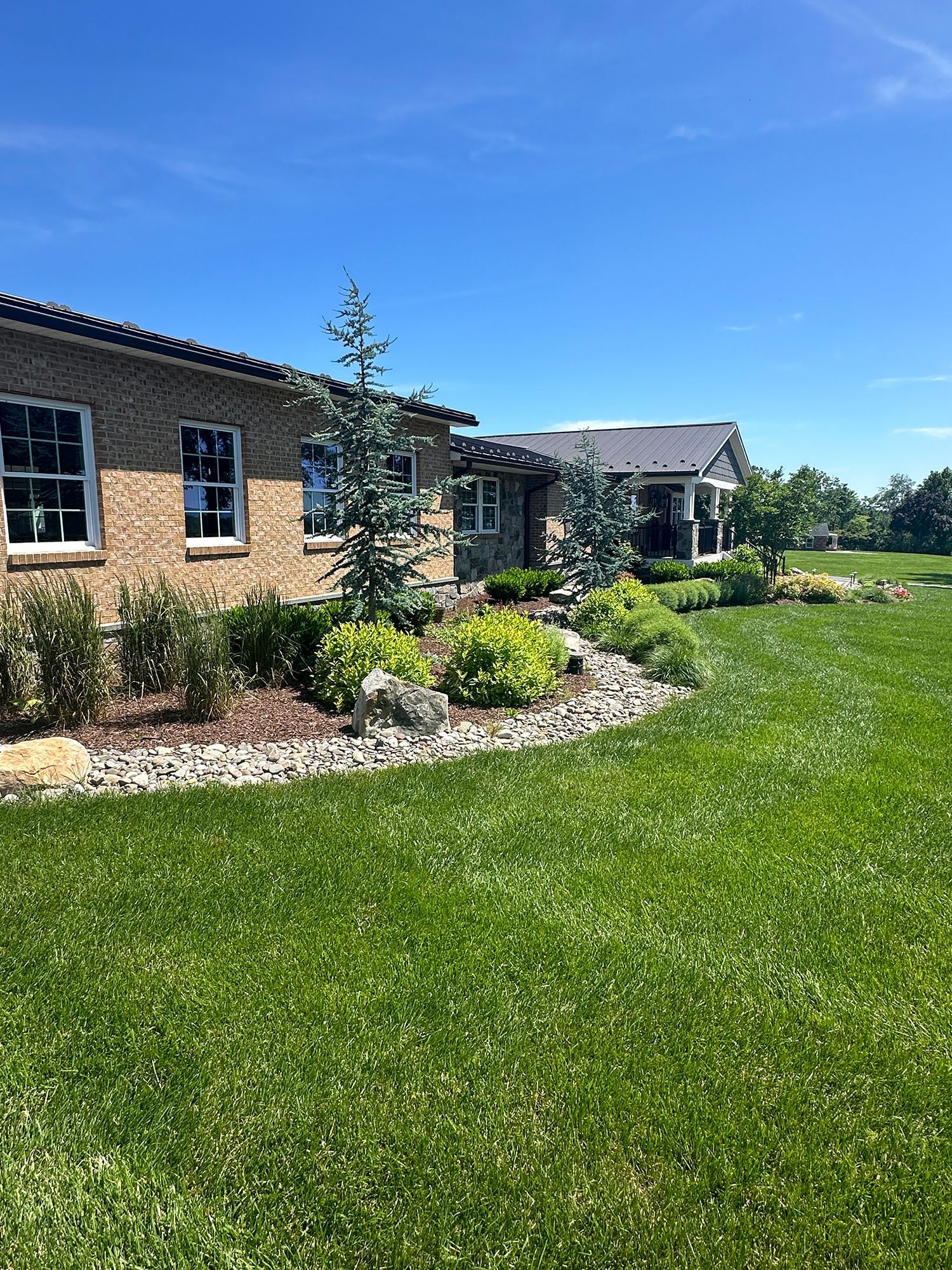 A large brick house with a lush green lawn in front of it.