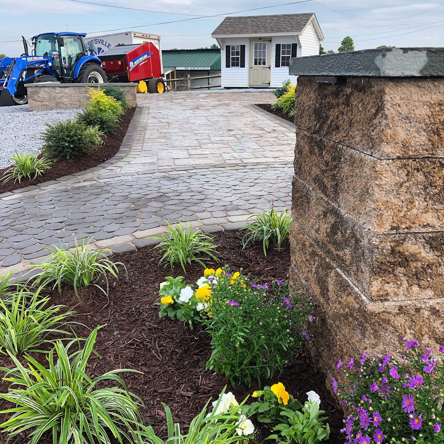 A tractor is parked on the side of the road next to a stone wall.