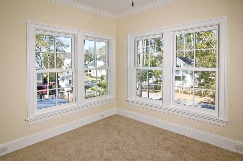 An empty room with three windows and a carpeted floor.