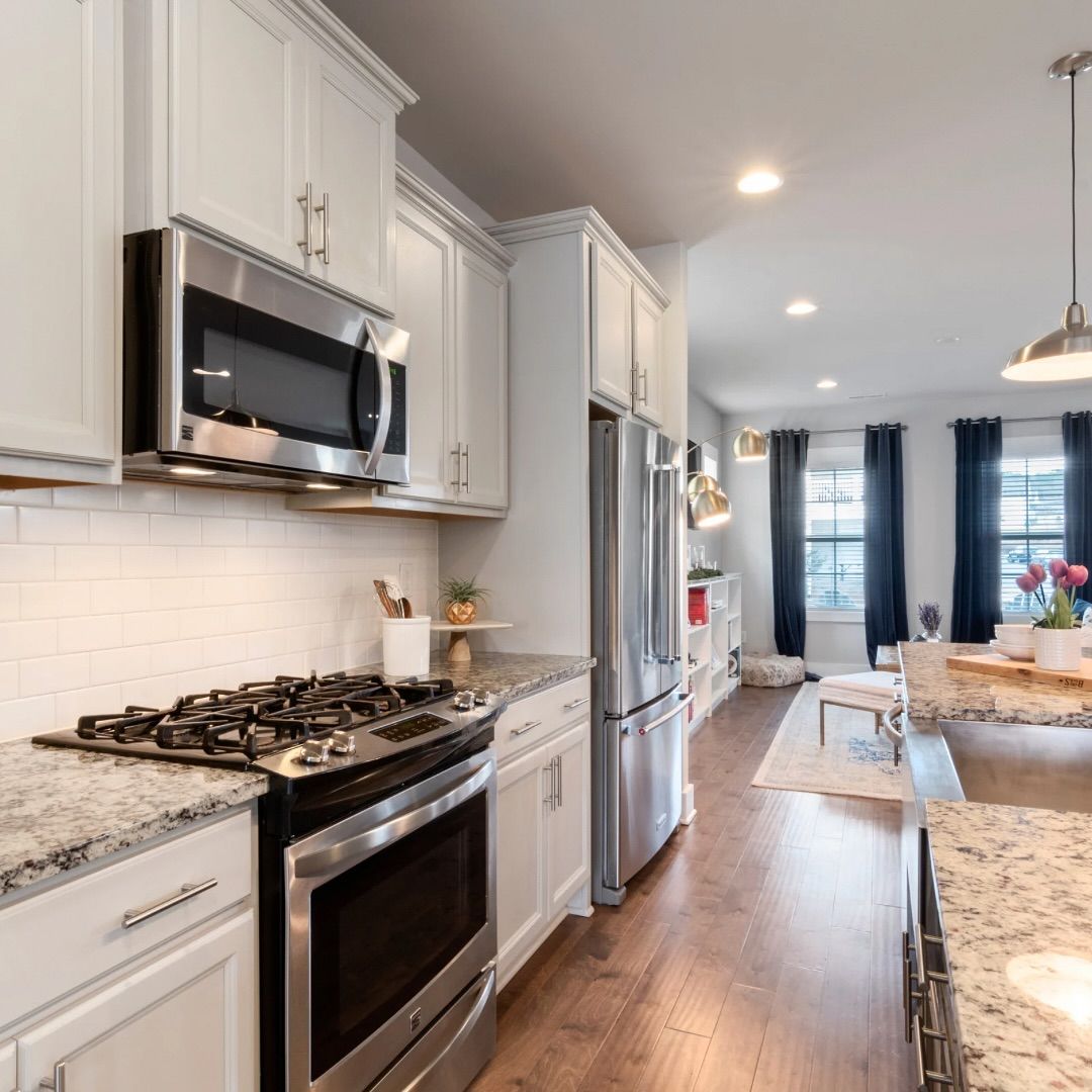 Bright kitchen with stainless steel appliances, white cabinets, granite countertops, and hardwood floors.