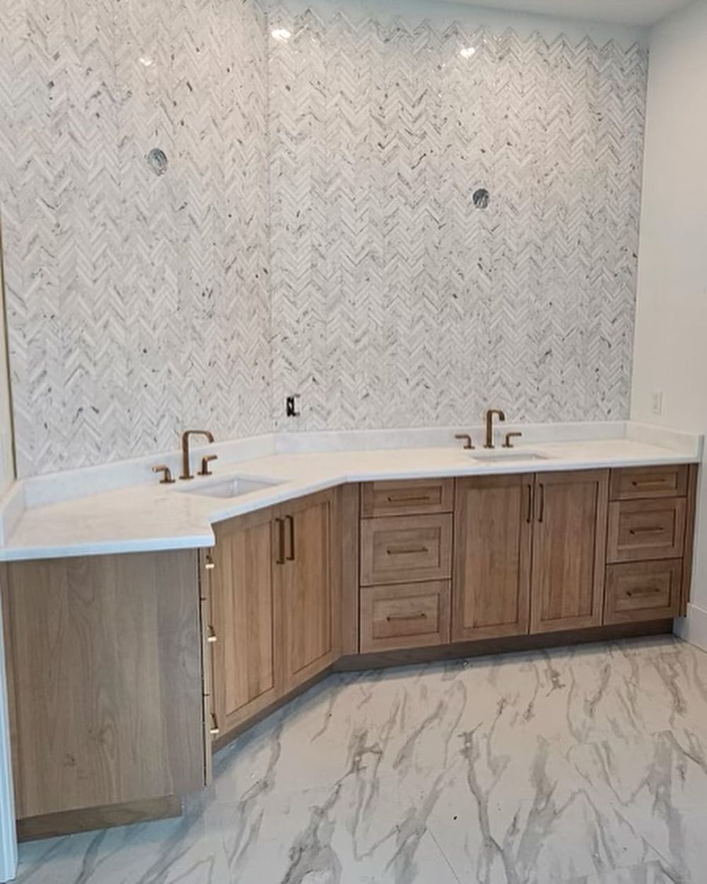 Bathroom with wooden cabinets, white countertop, and patterned tile backsplash. Two faucets are installed.