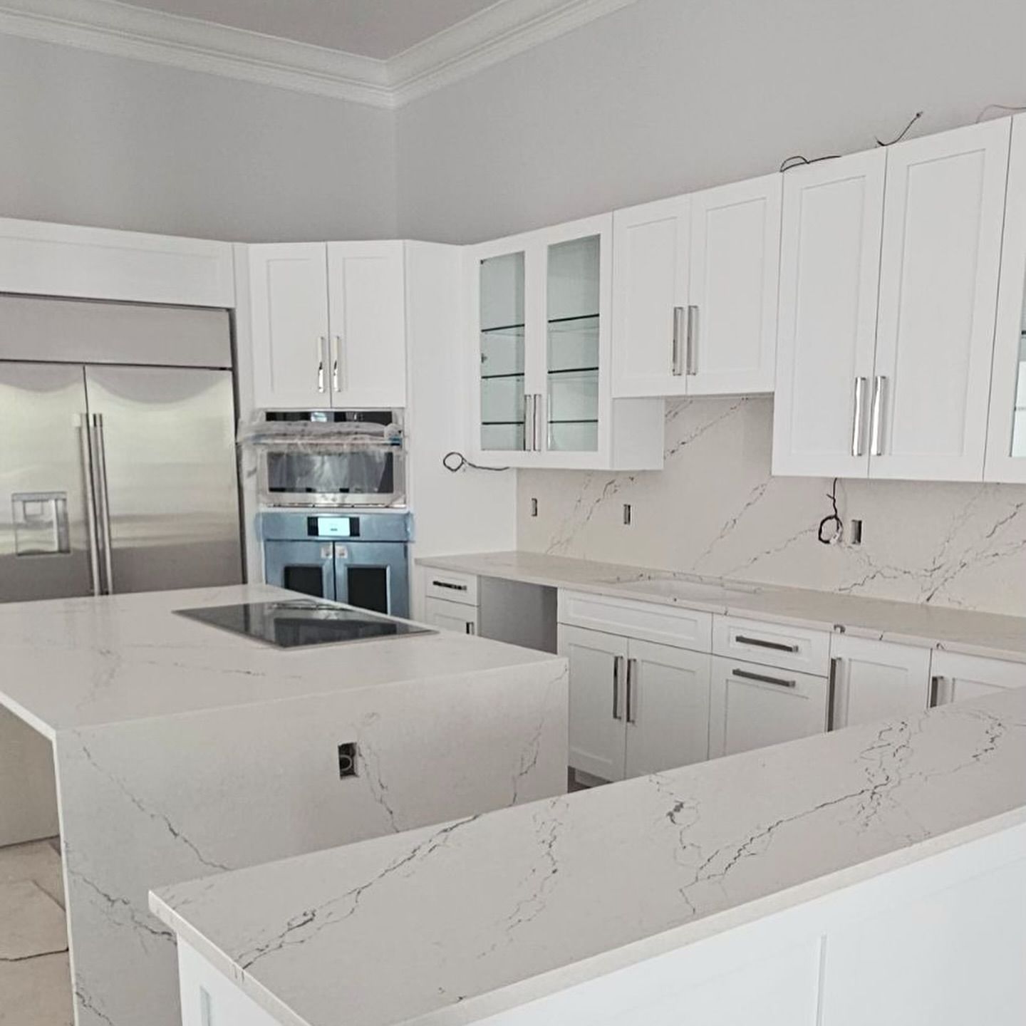 White kitchen with quartz countertops and stainless steel appliances.
