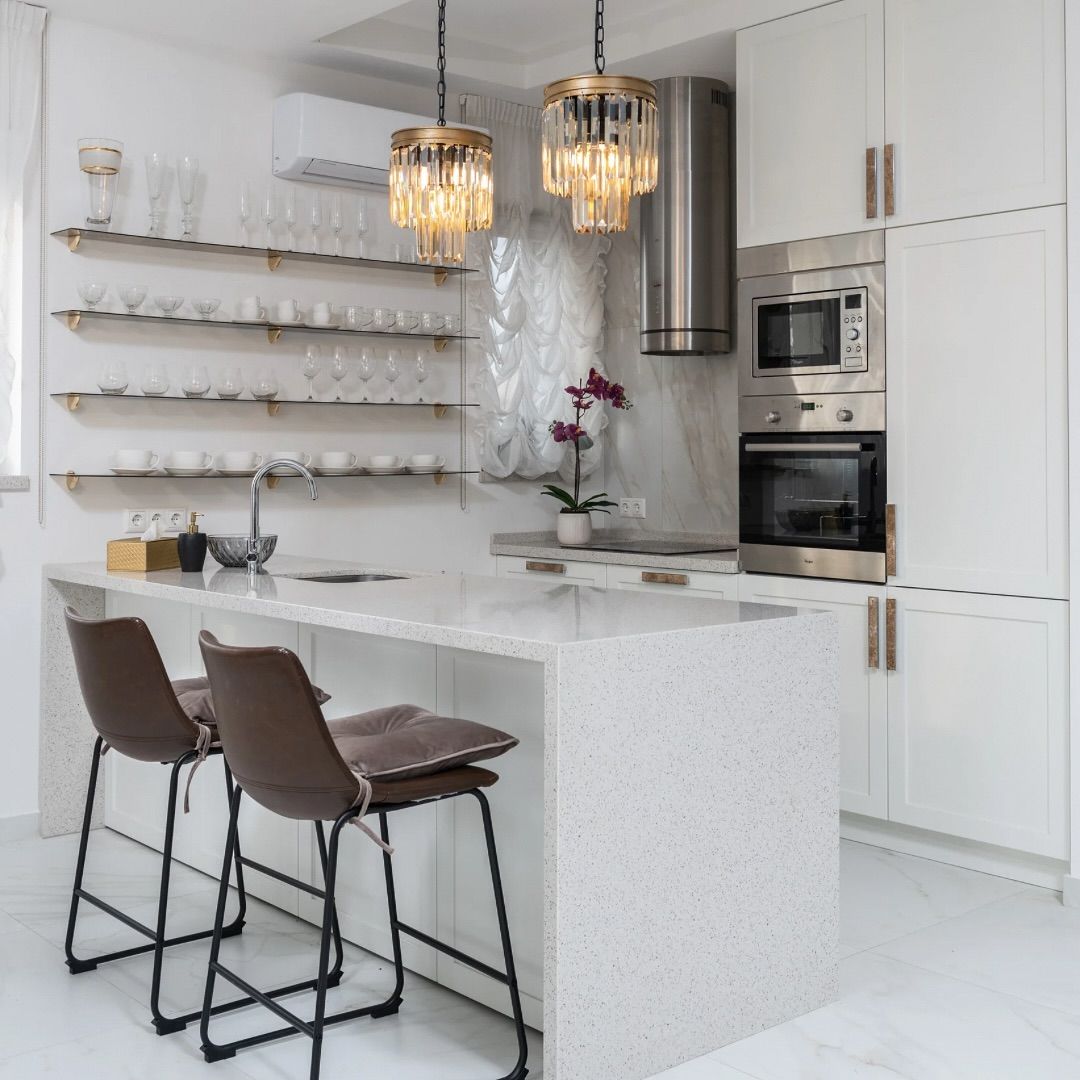 Modern kitchen with island, bar stools, glass shelves, and hanging lights.