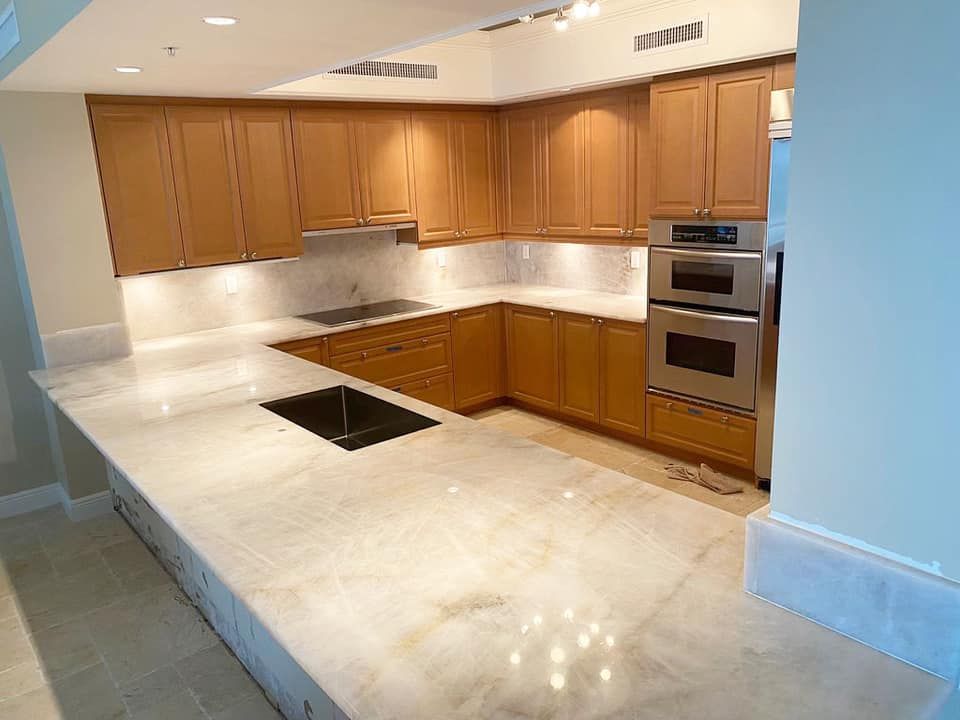 Kitchen with light wood cabinets, marble countertops, and stainless steel appliances.
