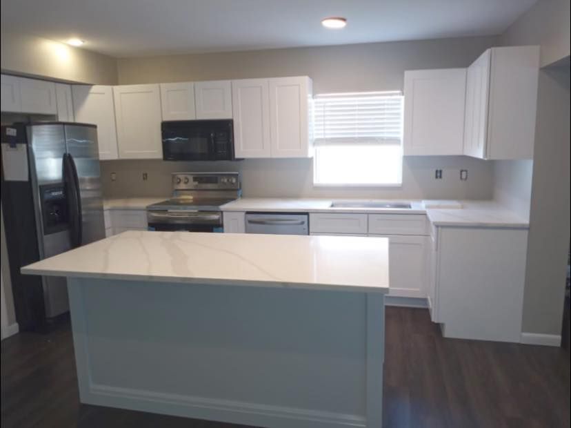 White kitchen with island, stainless steel appliances, and white cabinets.