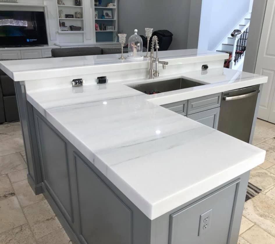 Gray kitchen island with white countertop, sink, and dishwasher.