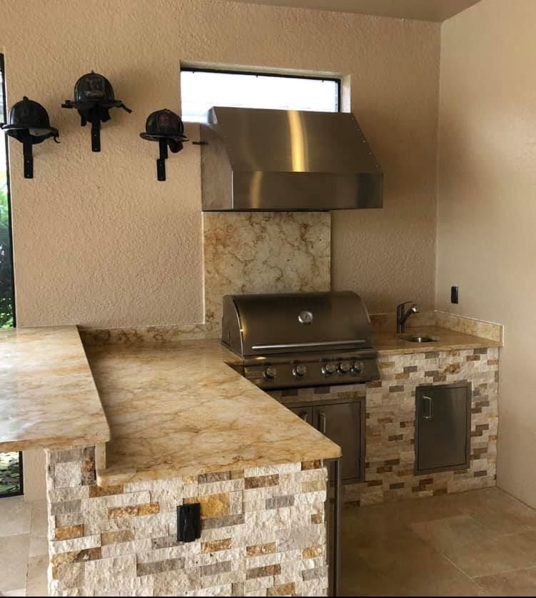 Outdoor kitchen with stainless steel grill, countertop, and stone facade.