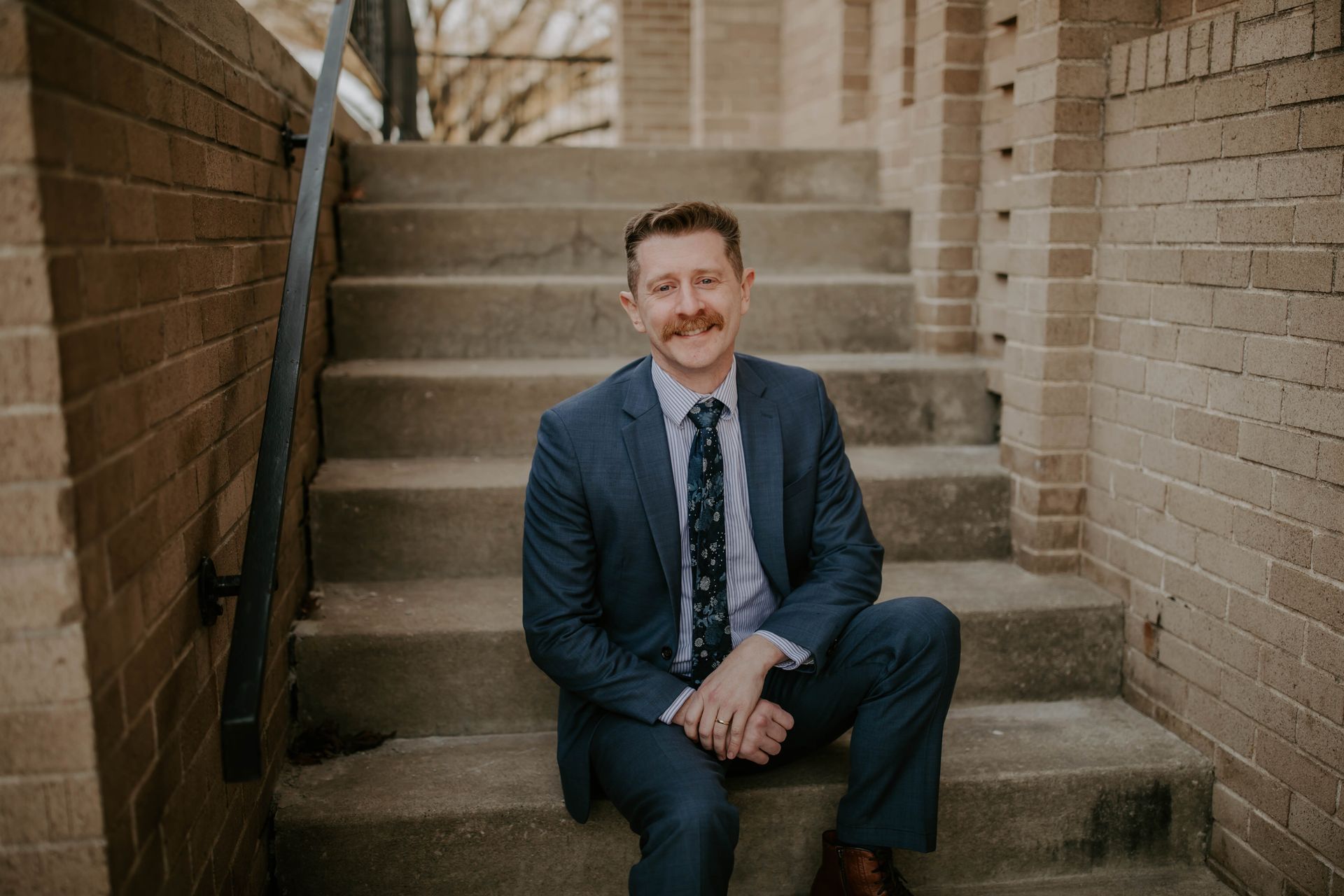 A man in a suit and tie is sitting on a set of stairs.