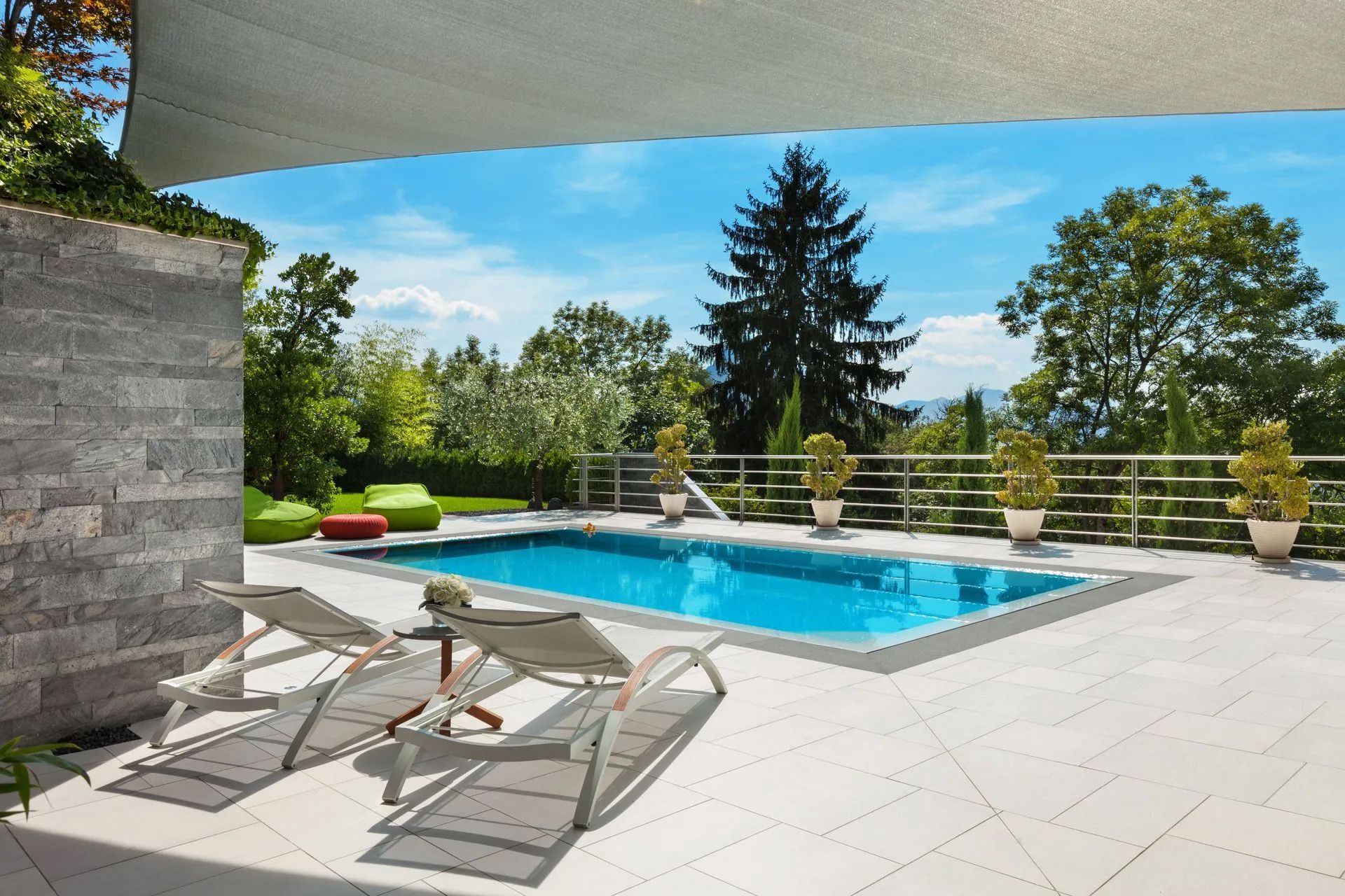 A large swimming pool is surrounded by chairs and trees