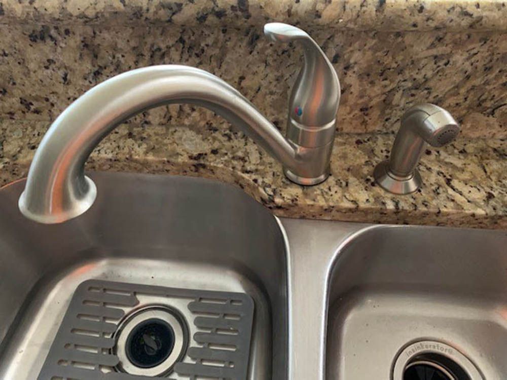 Kitchen sink with stainless steel faucet and soap dispenser on a granite countertop