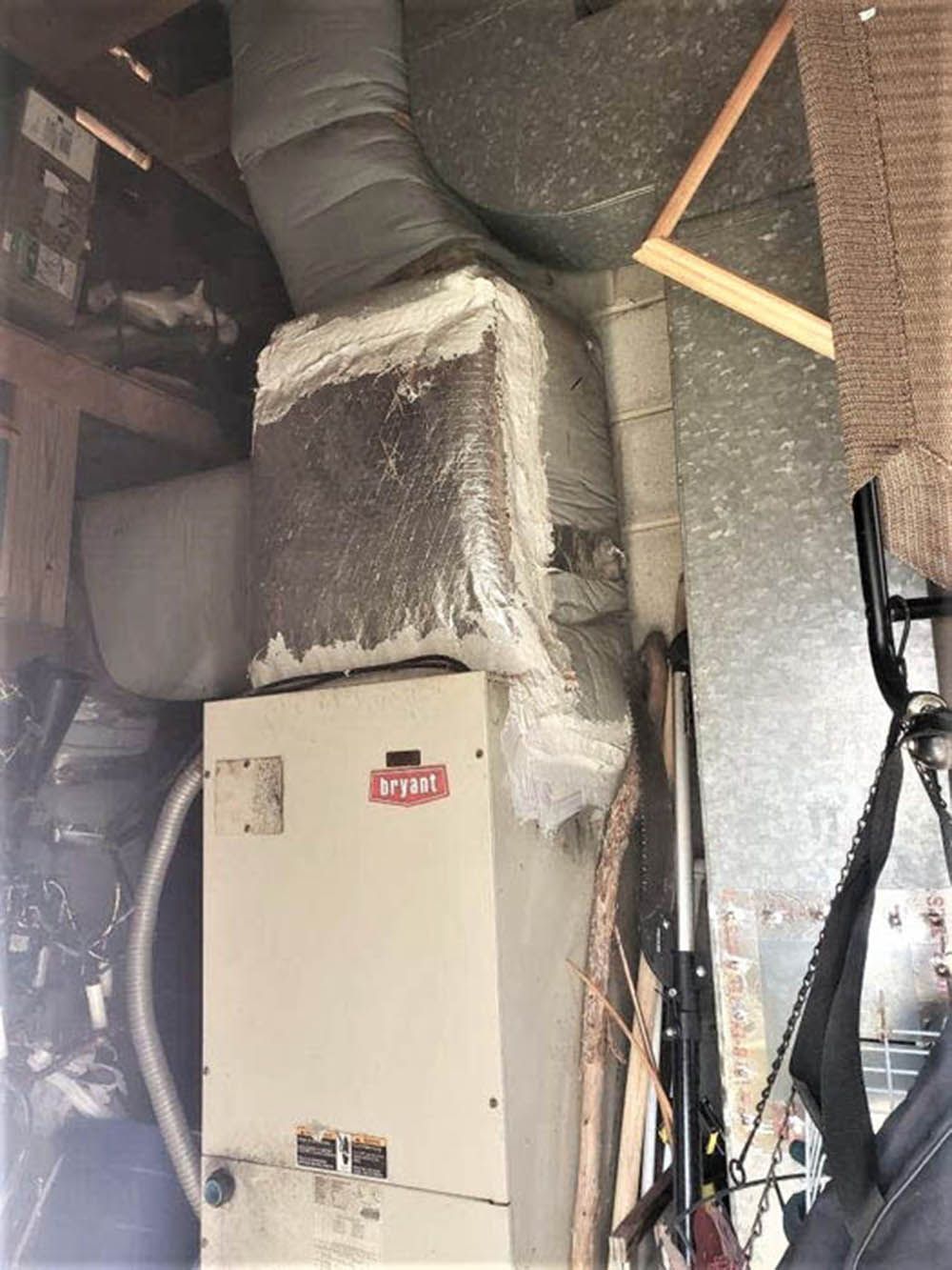 Basement HVAC furnace with insulated ductwork and exposed pipes in a utility room