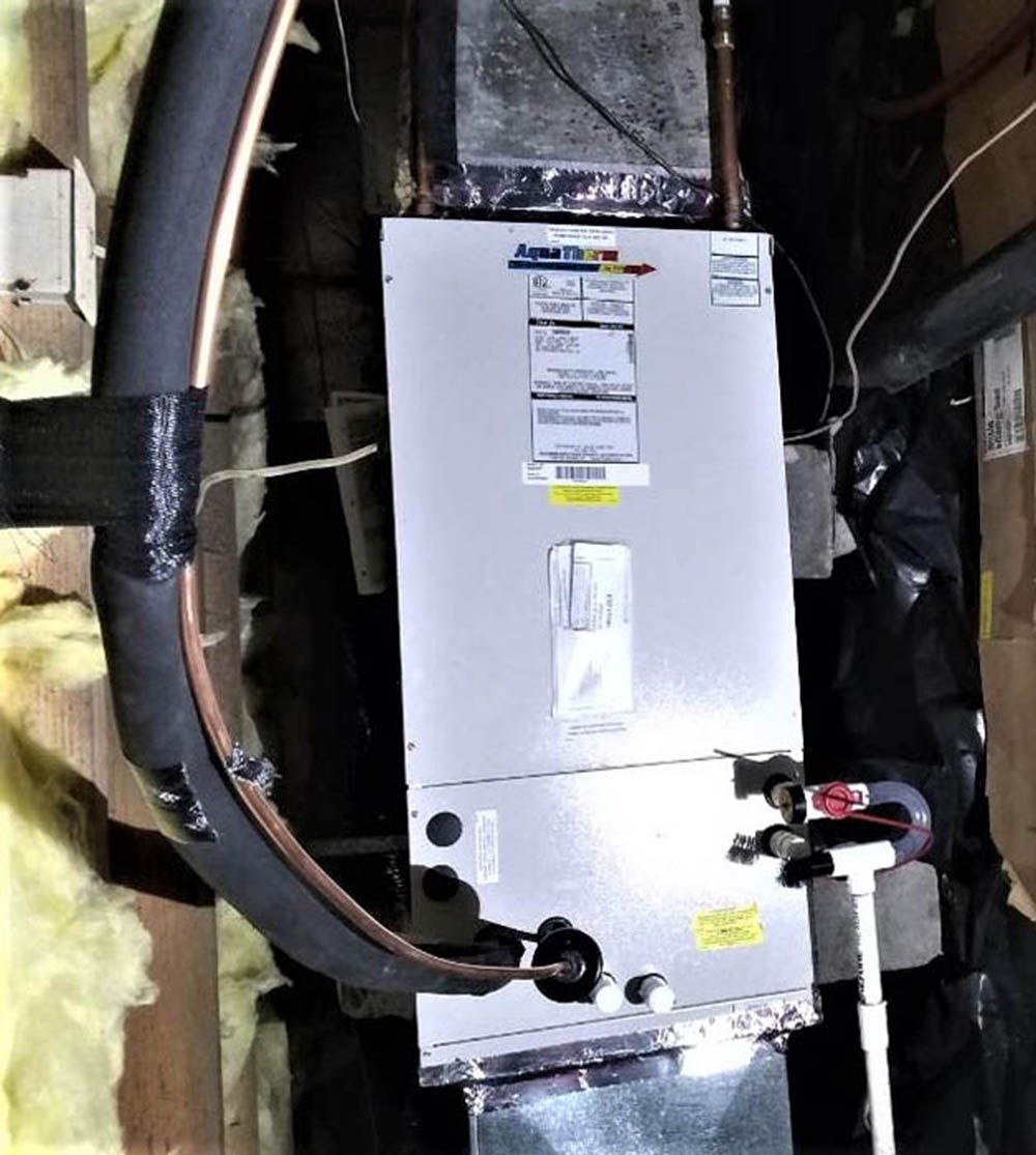 White HVAC/furnace unit with black insulated ducts and pipes in a utility closet