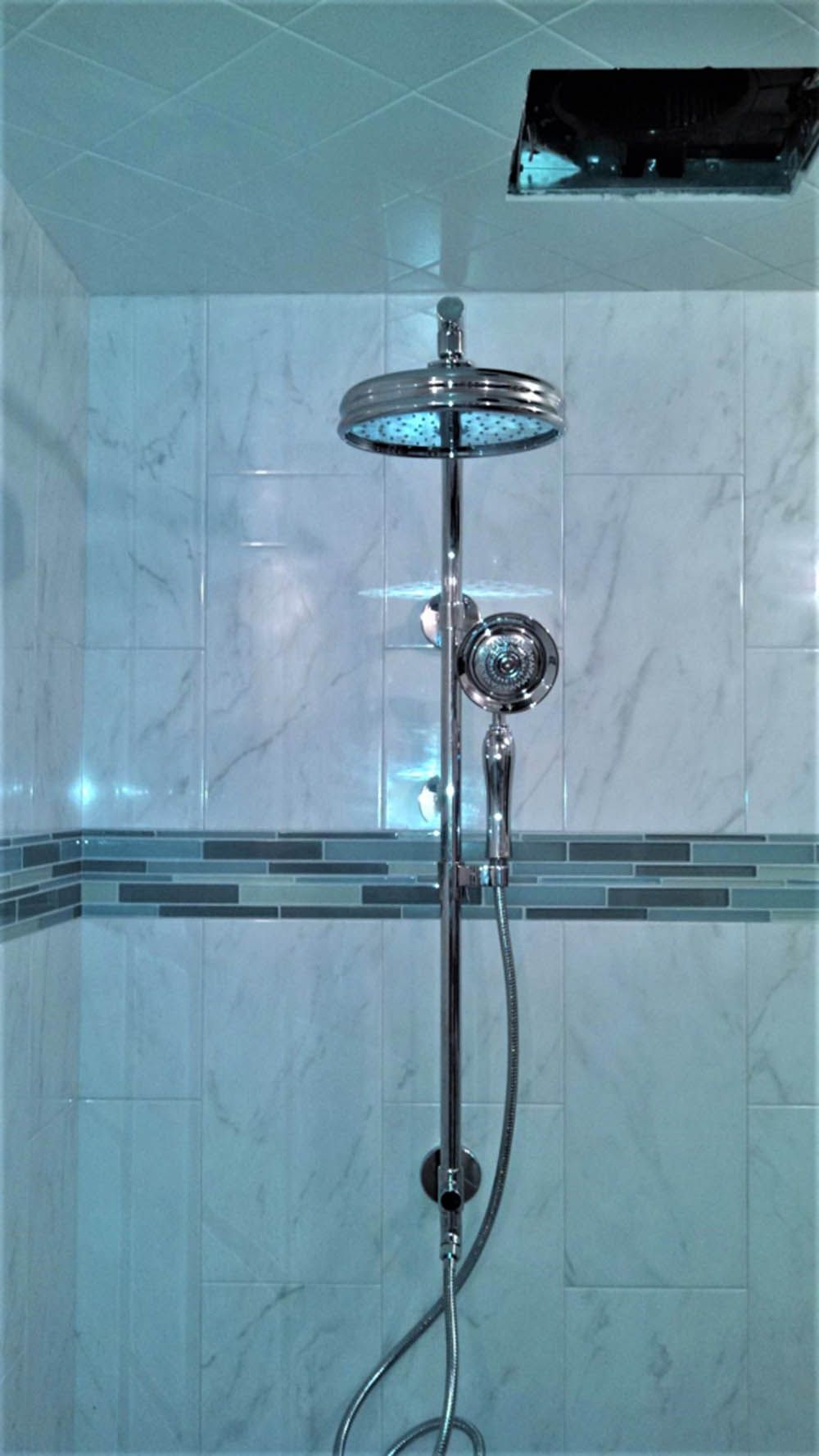 Modern tiled shower with a chrome rainfall showerhead and handheld wand