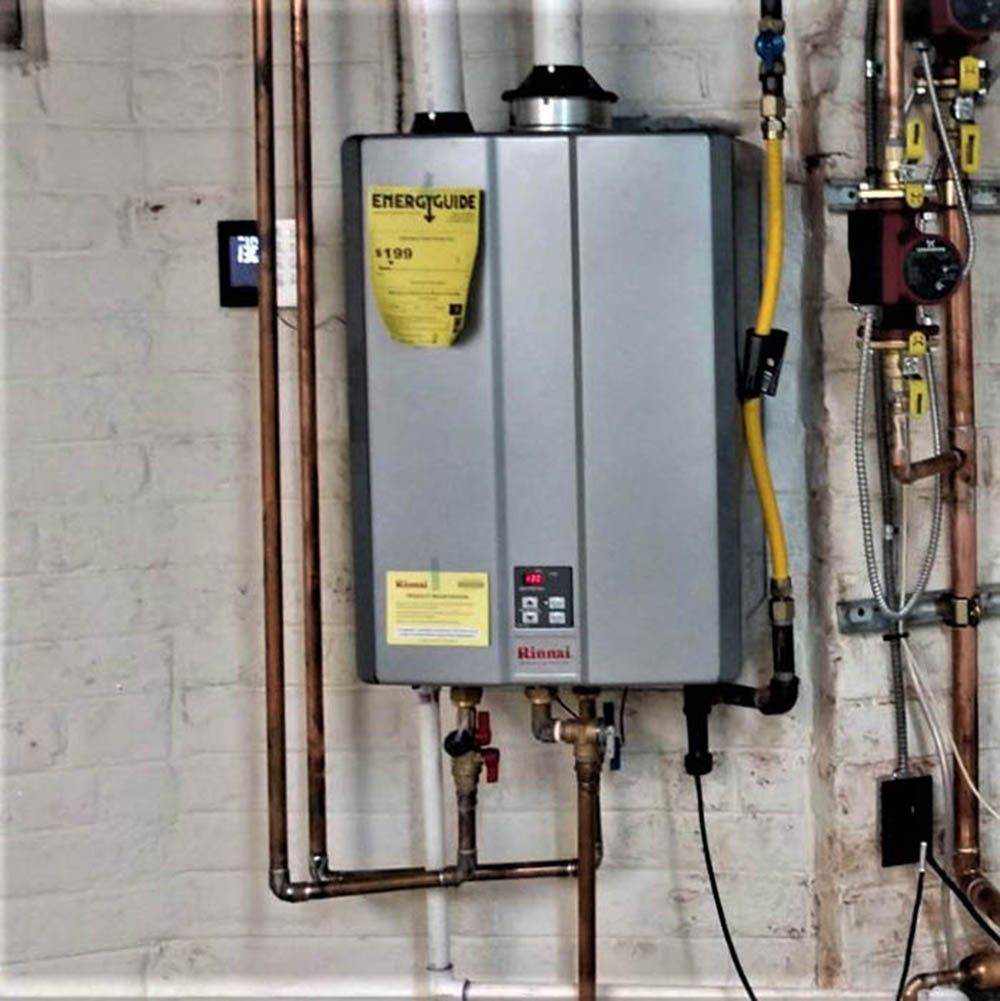 Wall-mounted gray tankless water heater with copper pipes and yellow gas line in a utility room