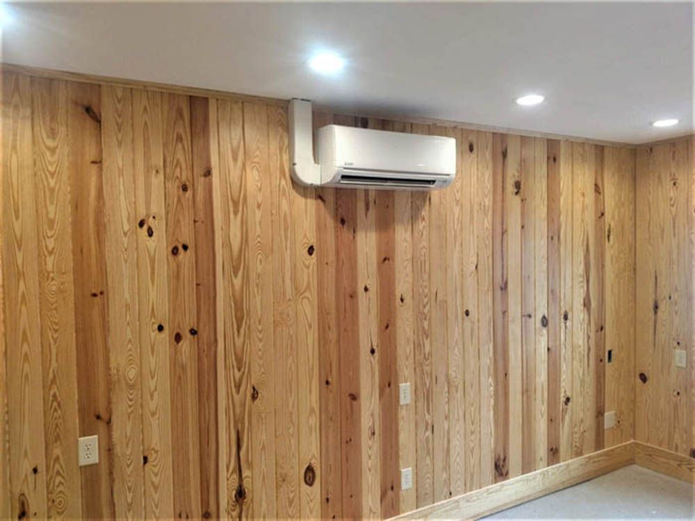 Wood-paneled room with a wall-mounted air conditioner and recessed ceiling lights