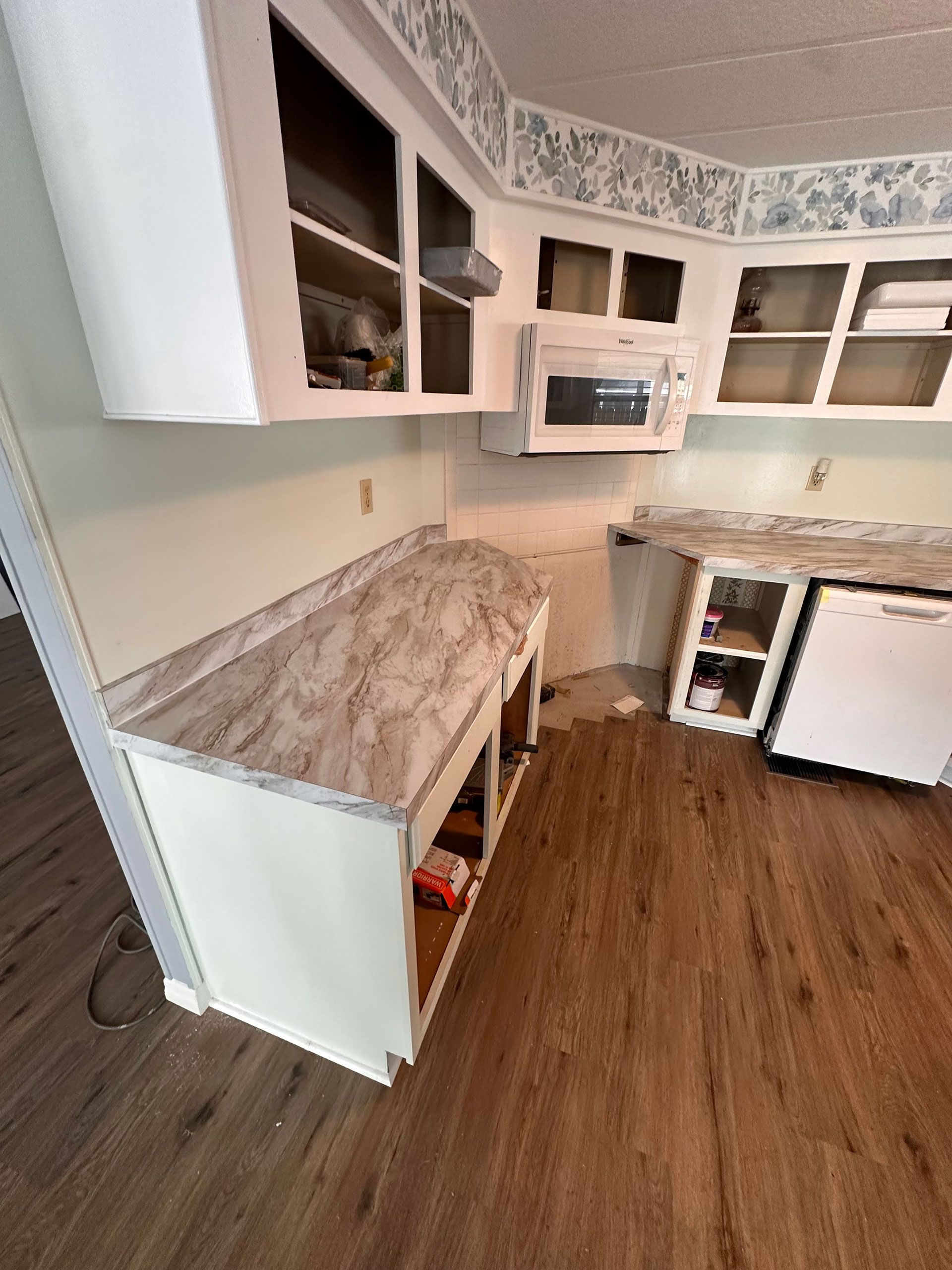 A kitchen with white cabinets, a microwave, and a dishwasher