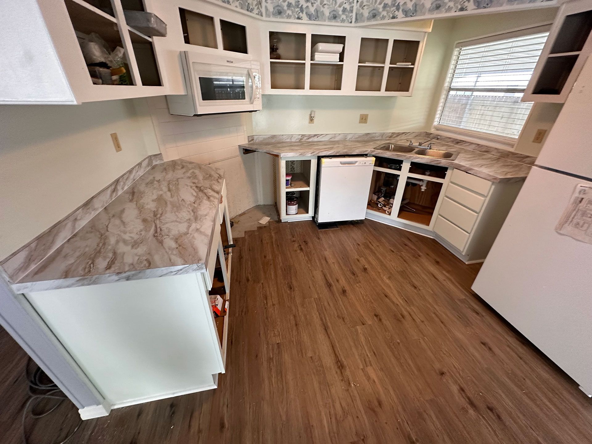 A kitchen with wooden floors and white cabinets