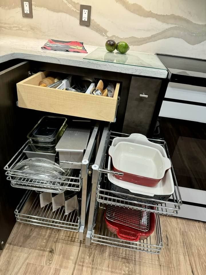 A kitchen with a pull out drawer filled with pots and pans