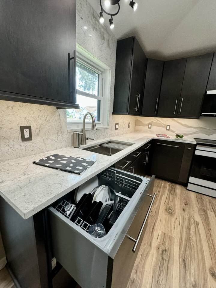 A kitchen with black cabinets and a dishwasher in the drawer