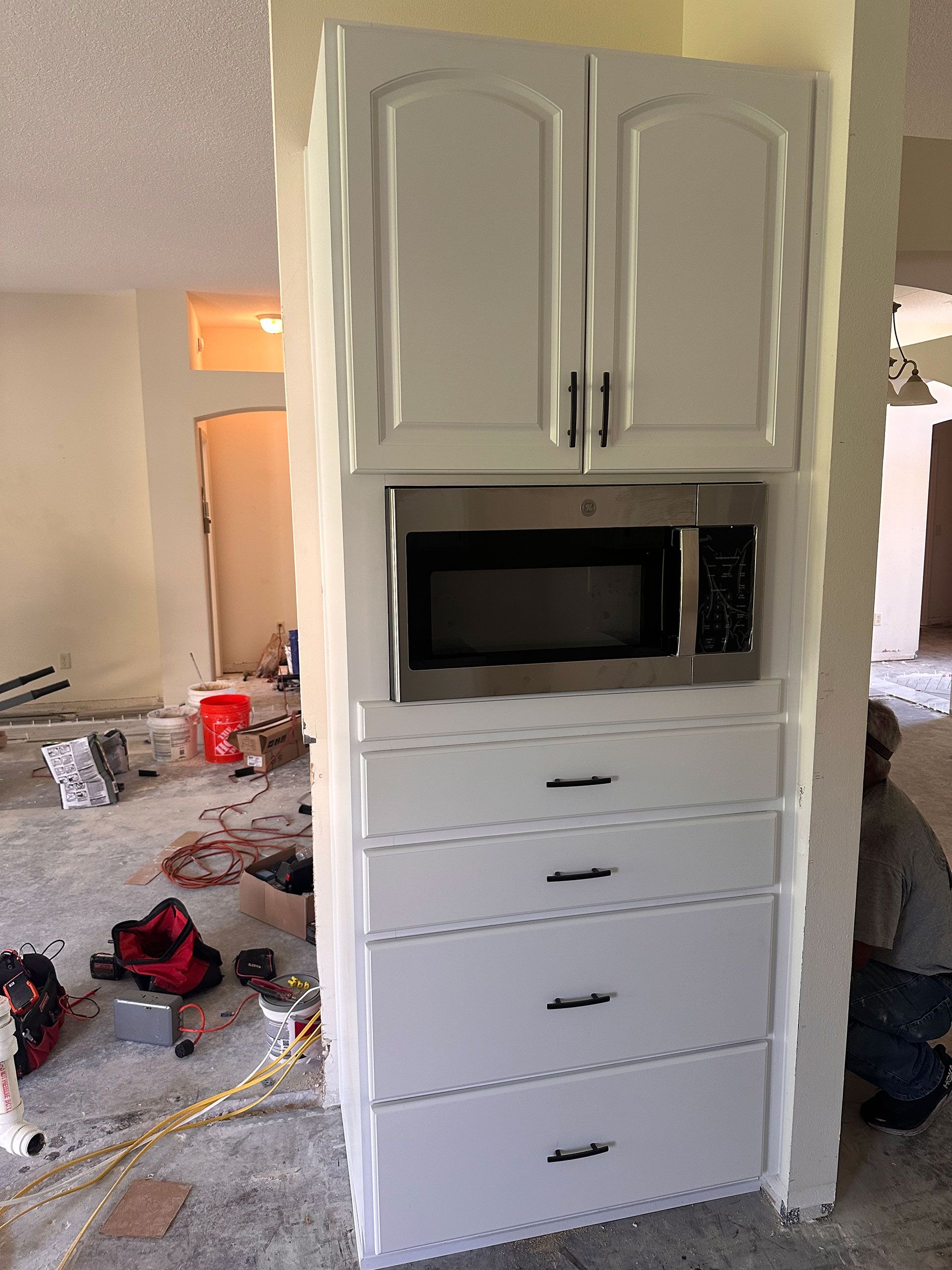 A microwave oven is built into a cabinet in a kitchen