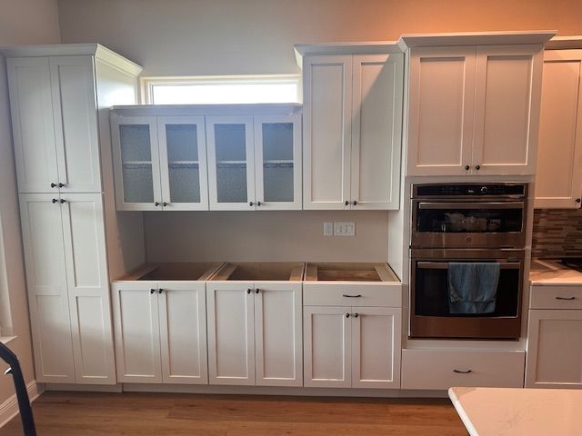 A kitchen with white cabinets and a stainless steel oven