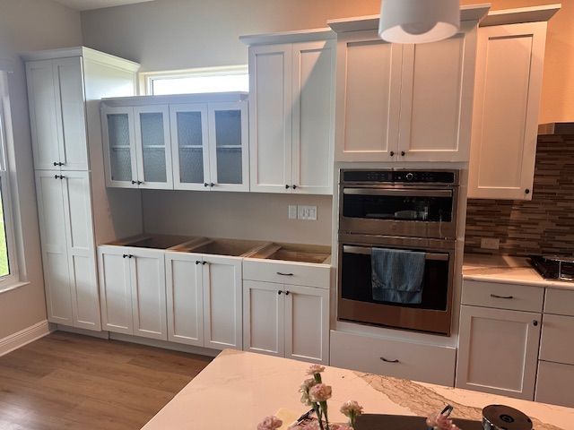 A kitchen with white cabinets and a stainless steel oven.