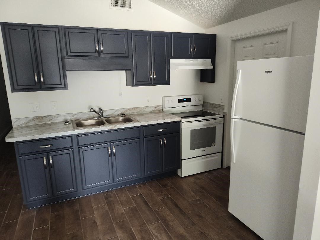 A kitchen with blue cabinets and a white refrigerator