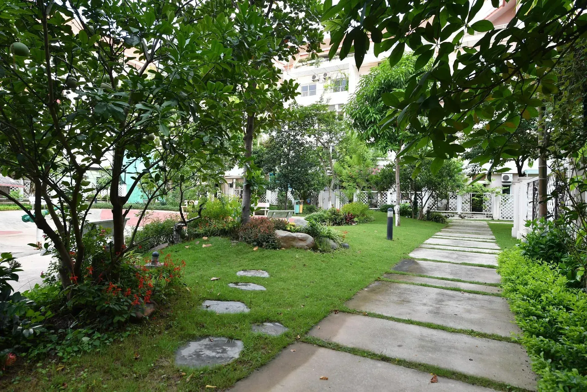 Pathway through a lush green garden with trees, stepping stones, and manicured landscaping.